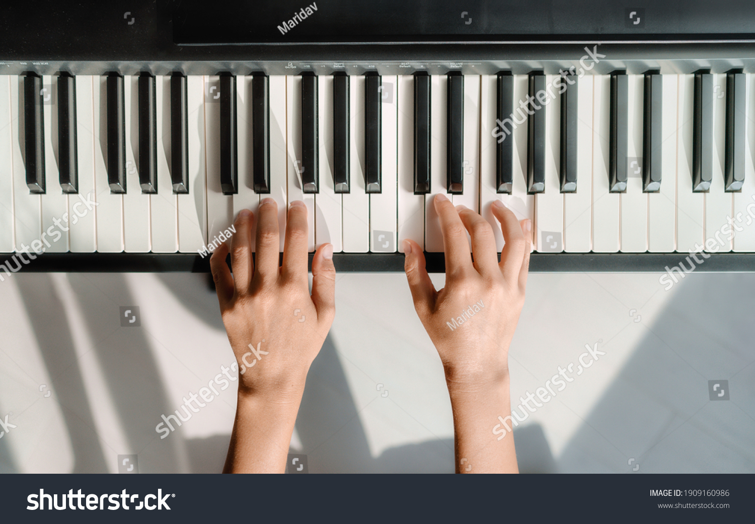 Piano learning chords at home - woman playing digital keyboard with online music lesson. Top view of musician hands on keys. #1909160986