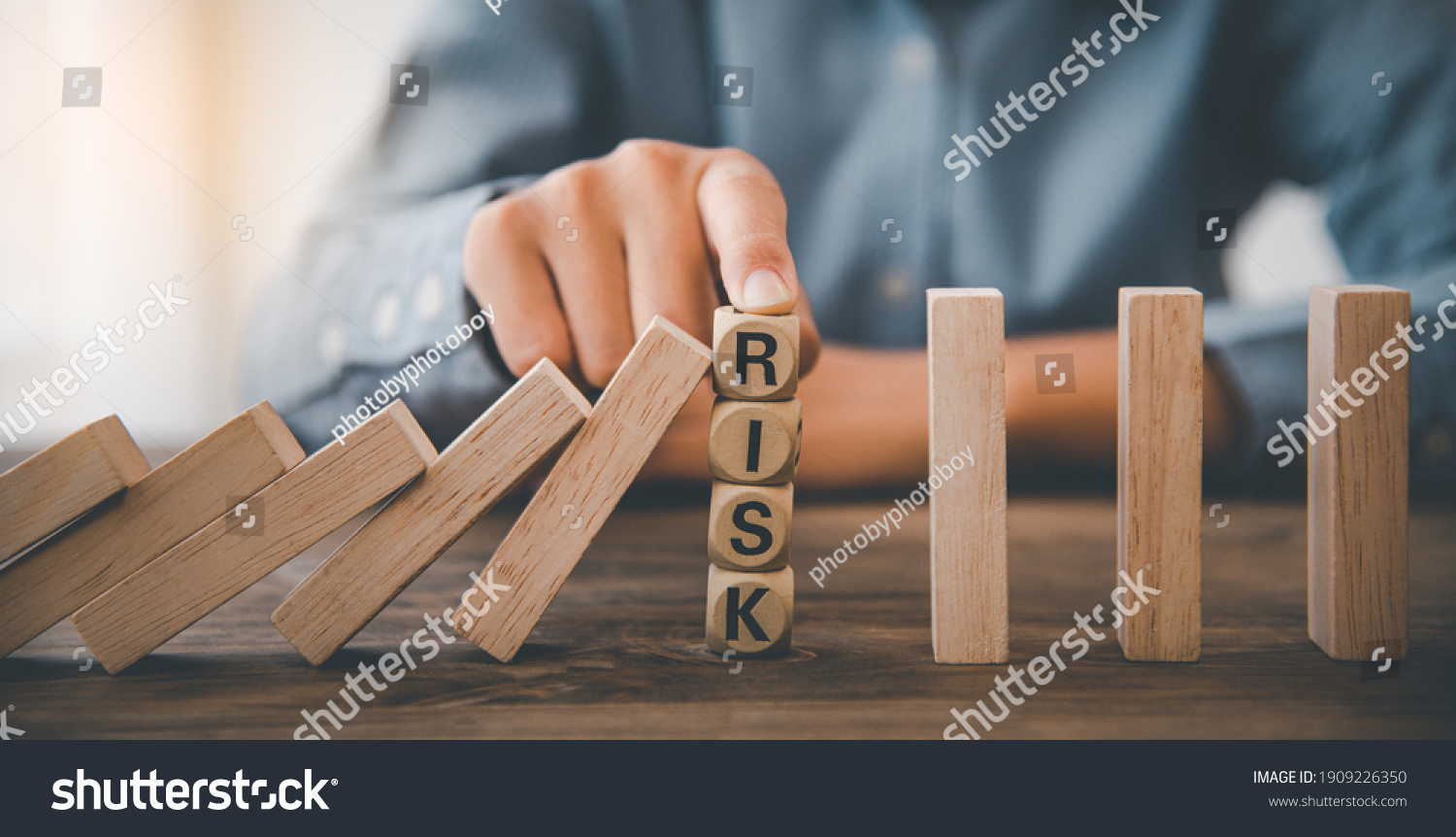 close-up hand The hand of a businessman who is stopping or preventing a falling block.Risk protection concept,Eliminating the risk #1909226350