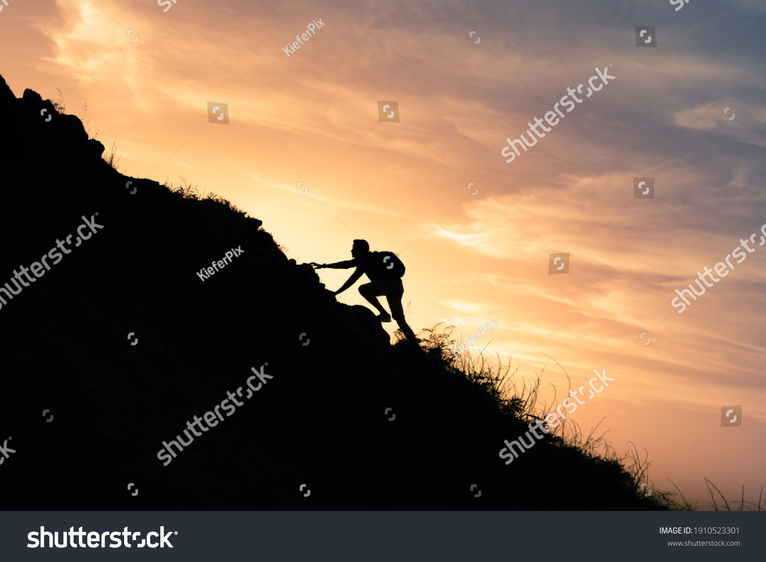 Young man climbing up to top of mountain. Self improvement and motivational goals concept.  #1910523301