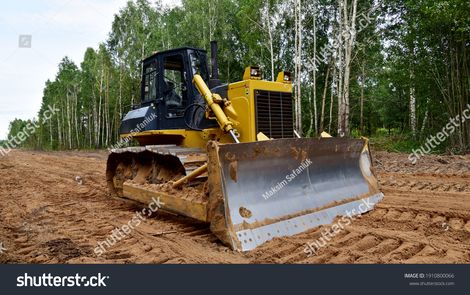 Dozer during clearing forest for construction new road . Yellow Bulldozer at forestry work Earth-moving equipment at road work, land clearing, grading, pool excavation, utility trenching #1910800066