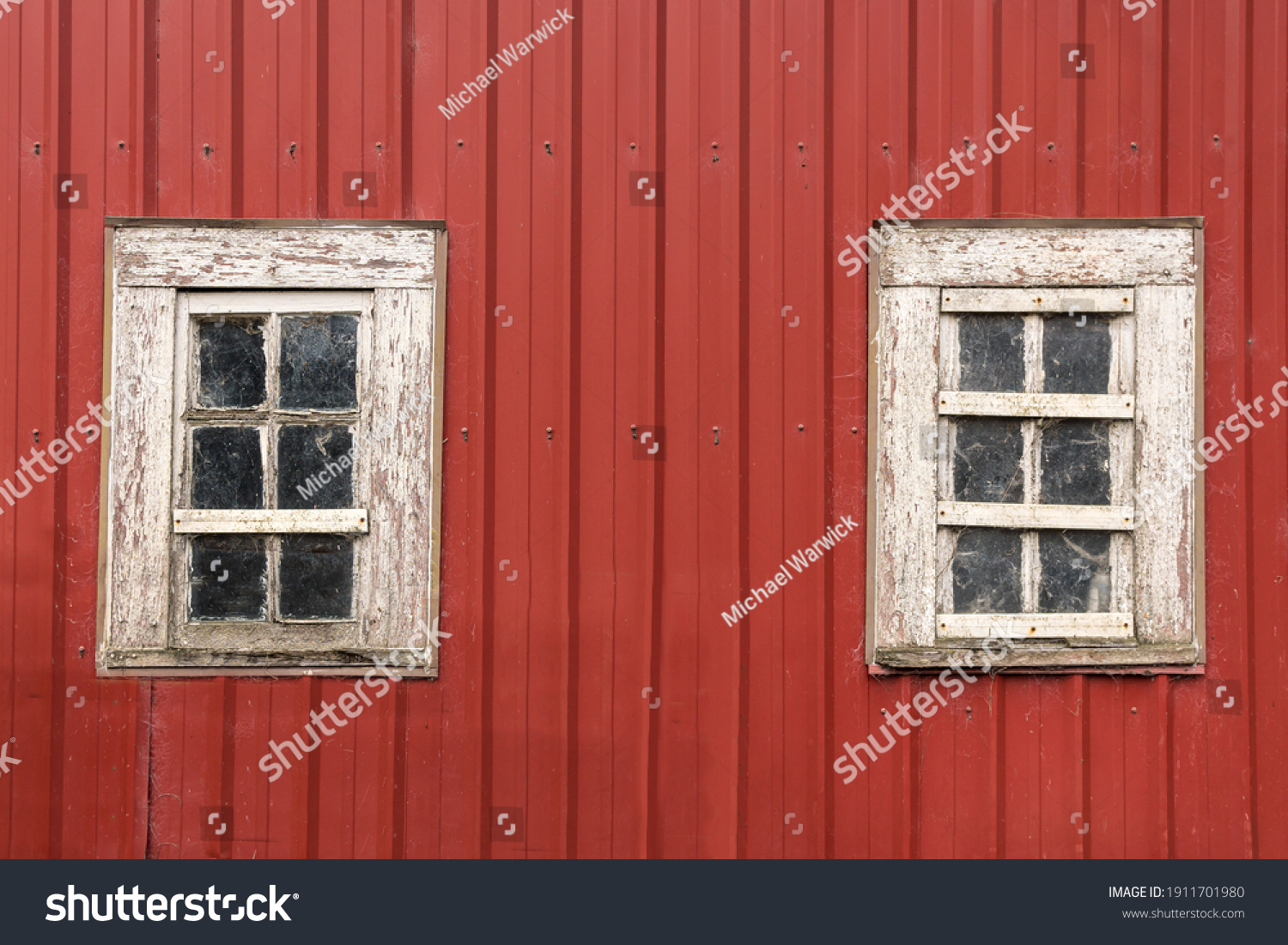 Old Red Barn with Two Weathered White Wooden Windows, Peeling Paint and Spider Webs. #1911701980