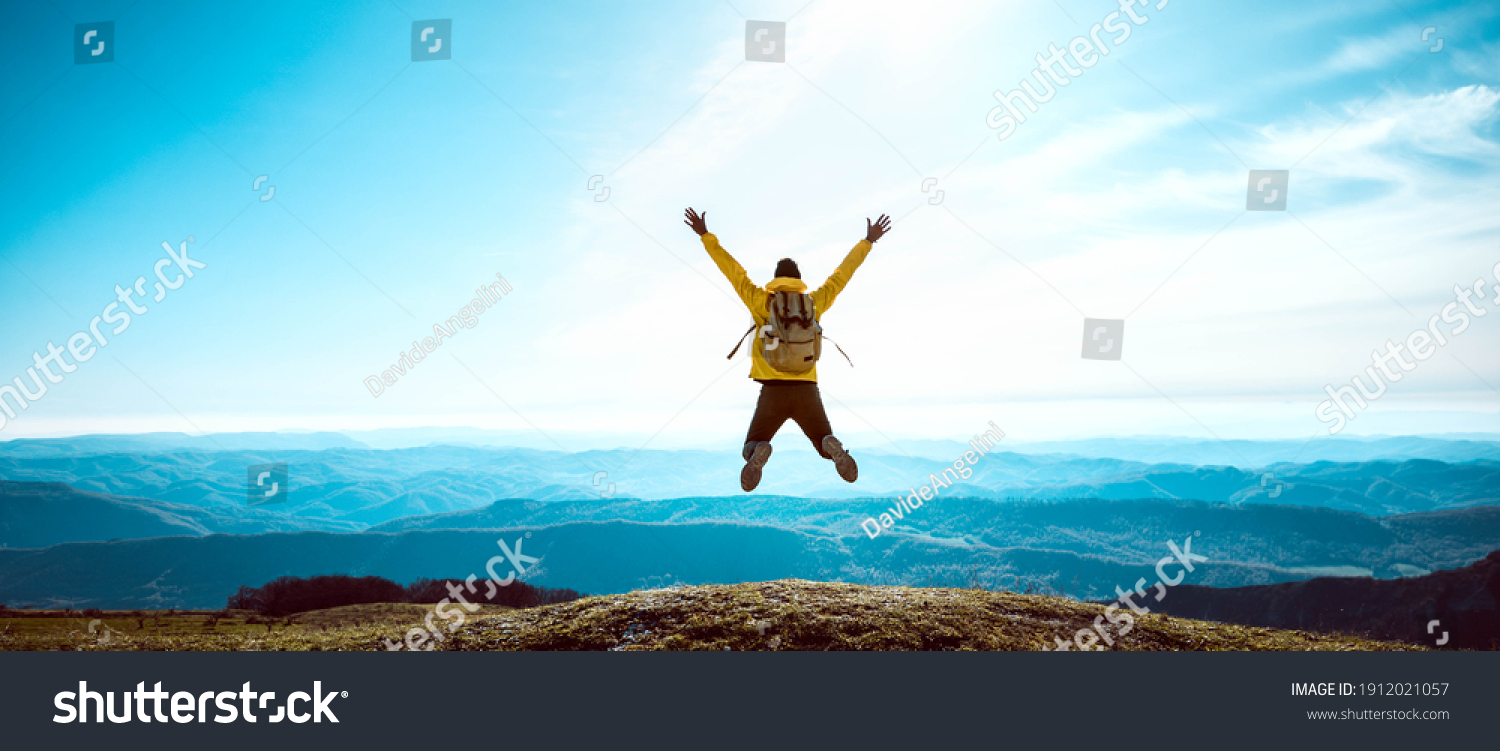 Happy man with open arms jumping on the top of mountain - Hiker with backpack celebrating success outdoor - People, success and sport concept #1912021057