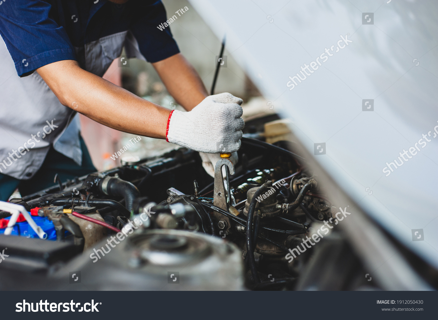 Mechanic uses a wrench to fix the car engine. #1912050430