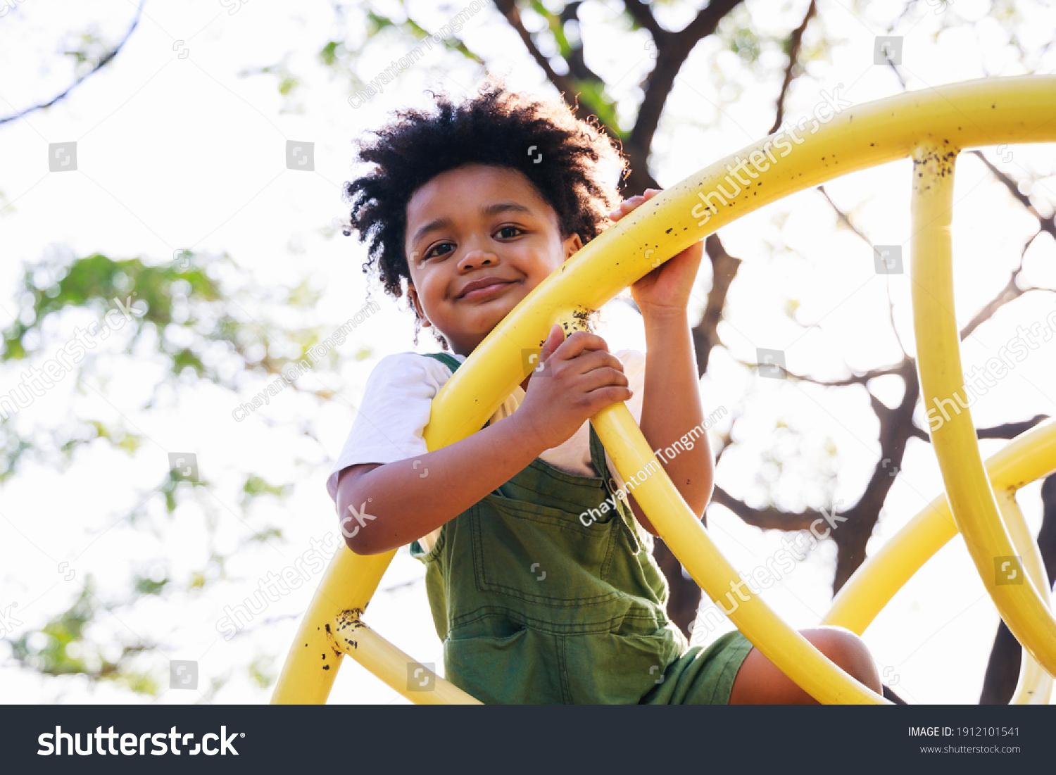 Cute African American little kid boy having fun while playing on the playground in the daytime in summer. Outdoor activity. Playing make believe concept. Outside education #1912101541