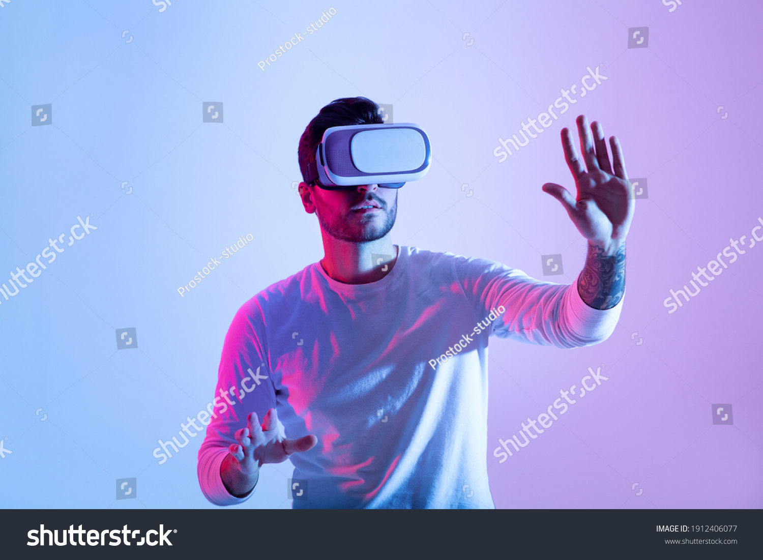 Amazing technology, online game, entertainment, study and virtual world in 3D simulation. Serious millennial man in vr glasses plays and tries to touch something, in neon, studio shot, free space #1912406077