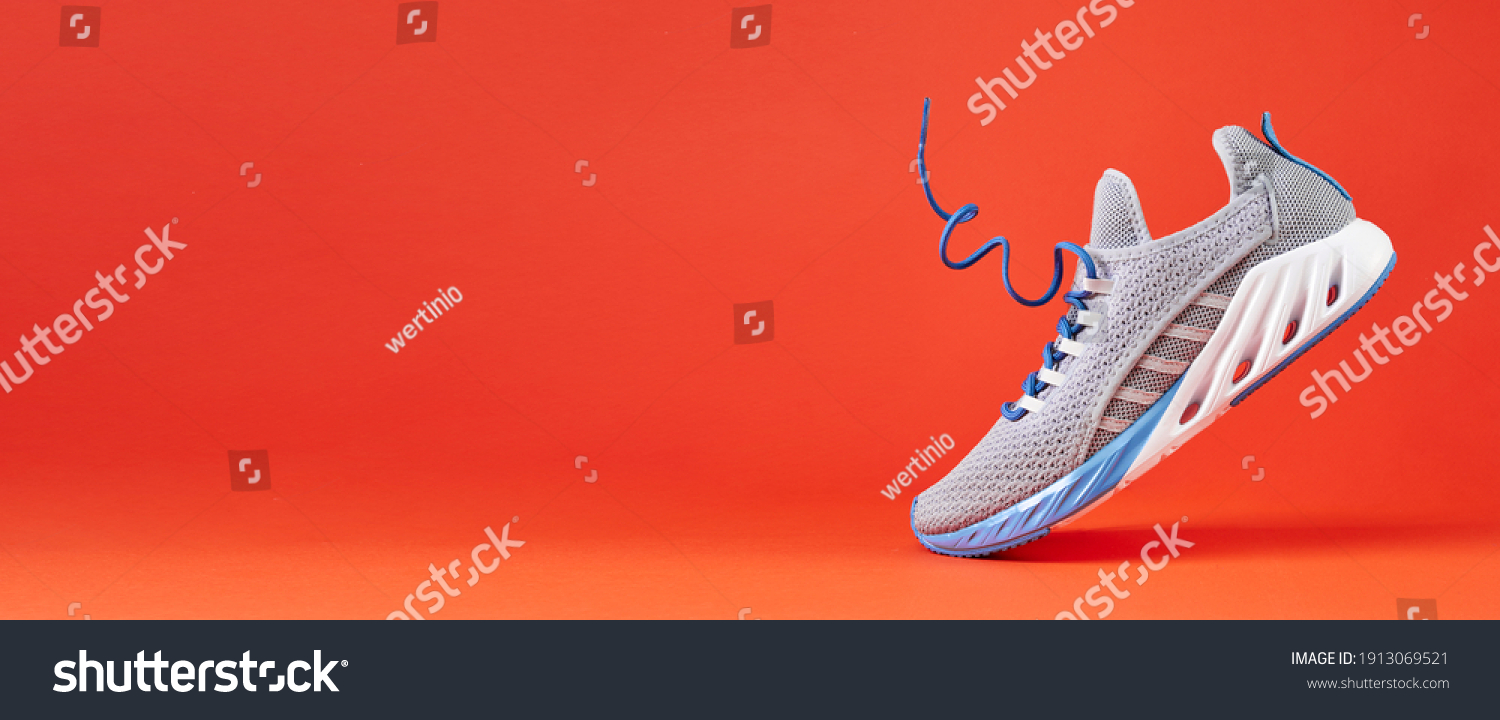 Fashion stylish sneakers with flying laces. Running sports shoes on orange background. Close up. #1913069521