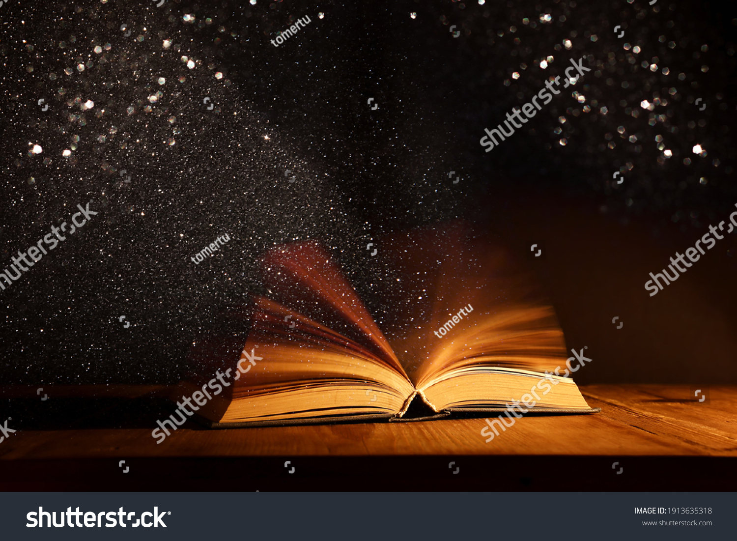 Magical image of open antique book over wooden table with glitter overlay #1913635318