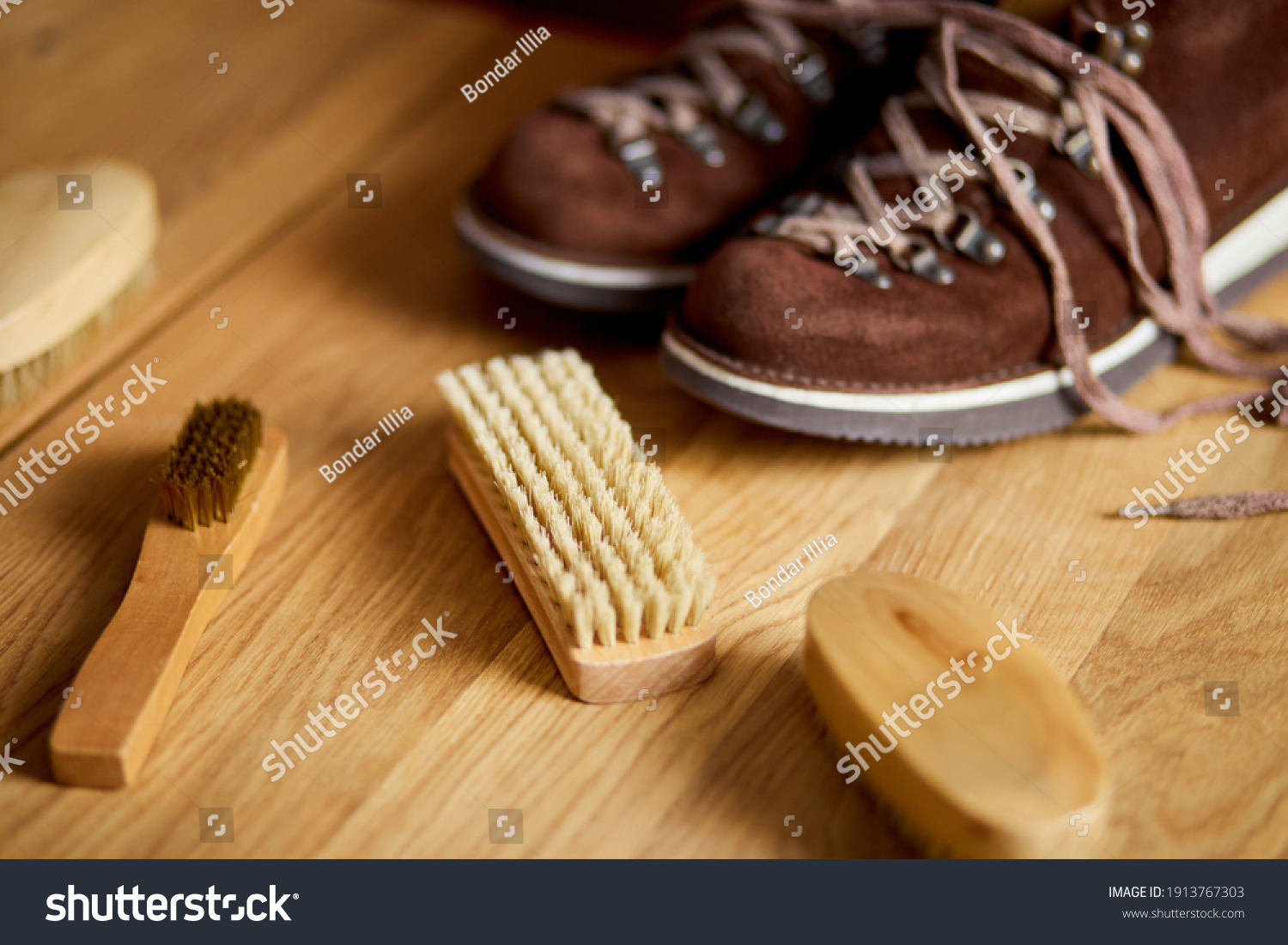 Flat lay, top view footwear with suede shoe boots care accessories, brush on wooden table. Footwear maintenance captured, copy space, for text. #1913767303