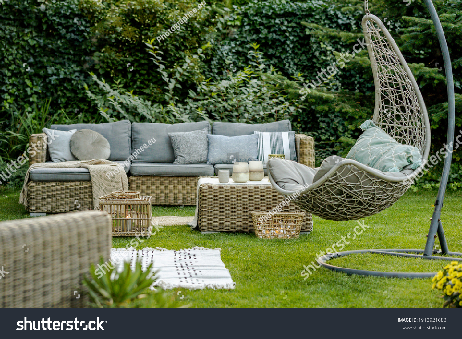 Comfortable wicker garden furniture with grey pillows in beautiful backyard #1913921683