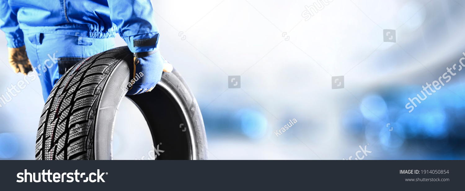 Mechanic holding tire with copy space for text repair service center, blurred background, Maintenance transport  panorama or banner photo. #1914050854
