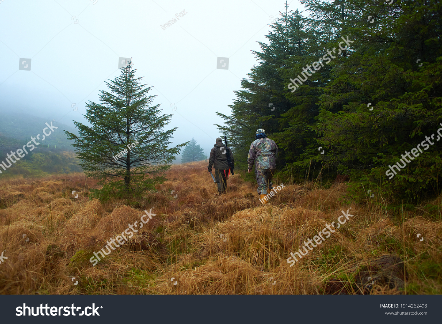 Two hunters in the forest during the day with moss and grass. #1914262498