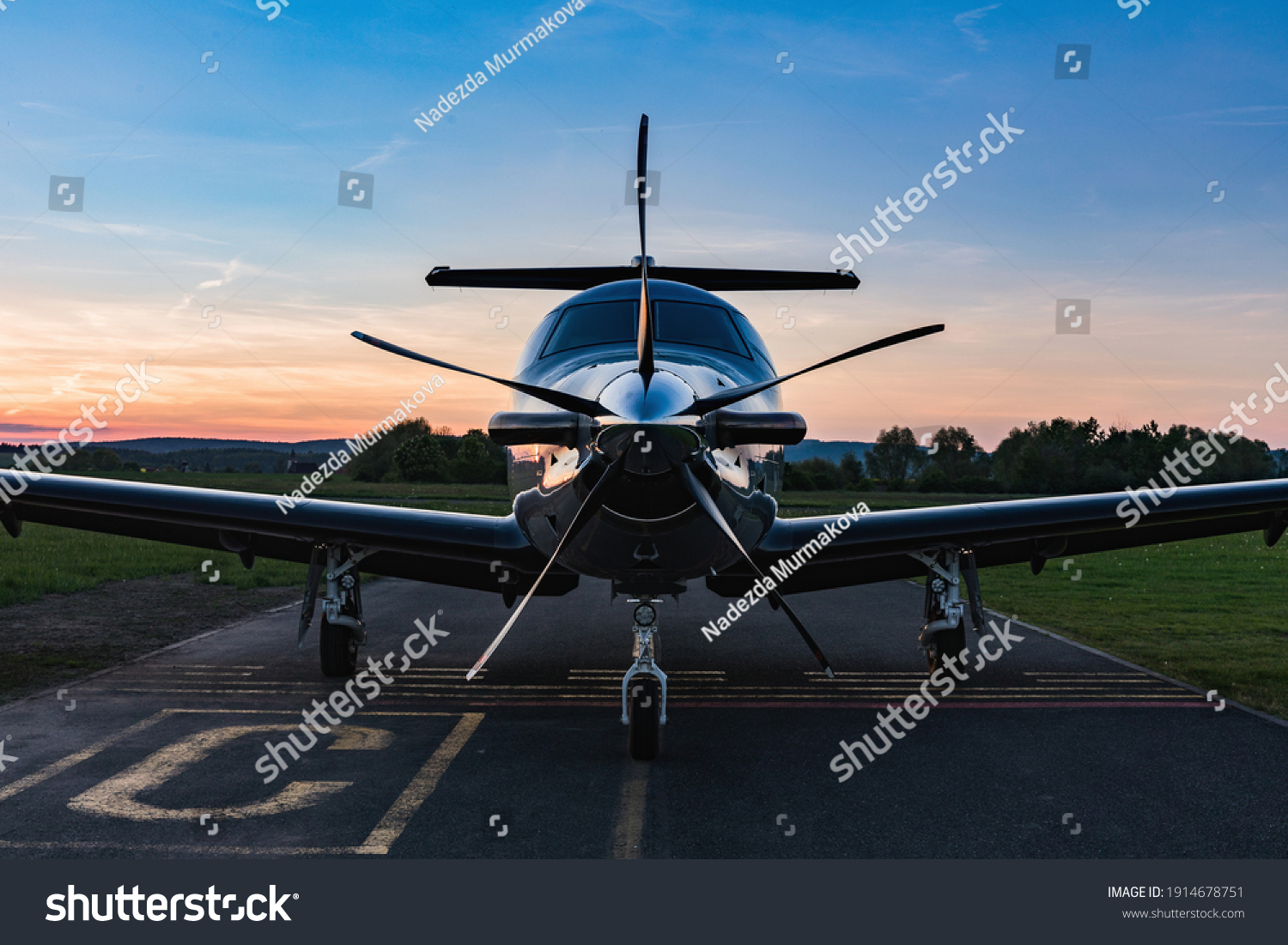 Single turboprop aircraft on evening runway after sunset. A single-engine plane is parked on the runway, bathed in the evening sun. Beautiful color view of the plane. #1914678751