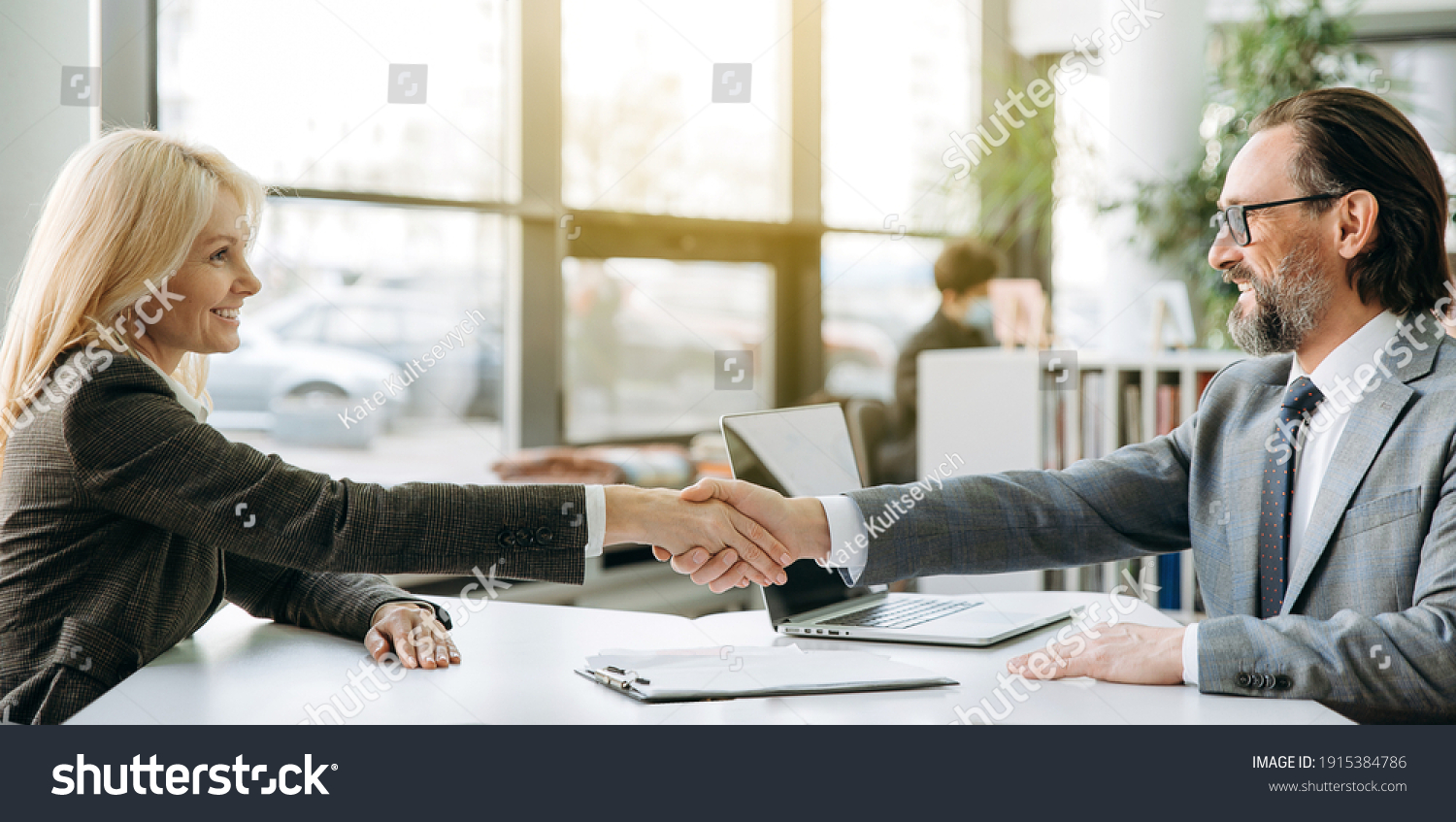 Confident business partners is shaking hands at meeting or after successful negotiations, sitting in modern office. Influential employees sign an important contract or deal, collaboration concept #1915384786
