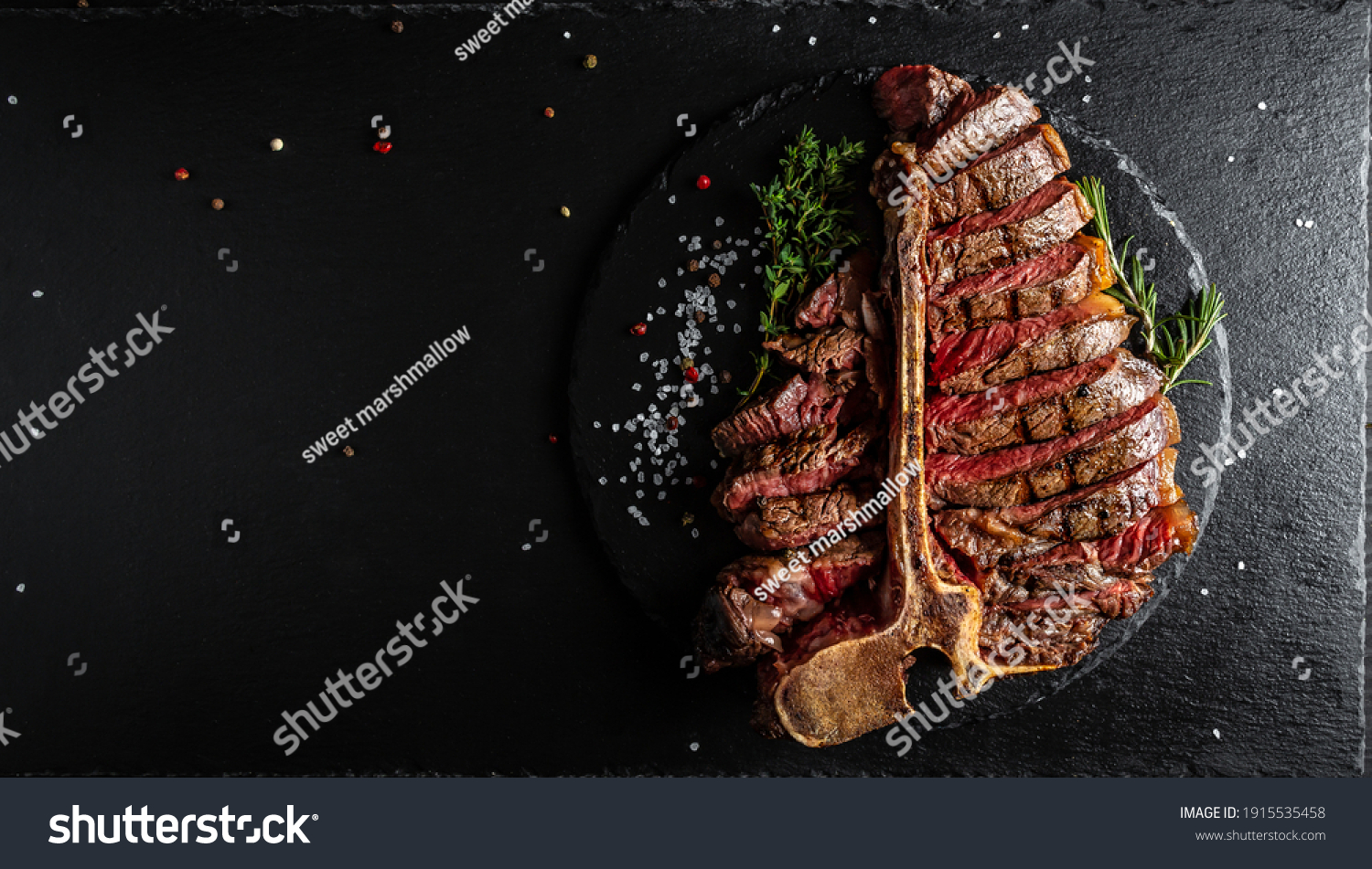 Barbecue dry aged wagyu porterhouse steak, grilled medium rare beef steak with spices served on slate board. sliced. Long banner format, top view. #1915535458