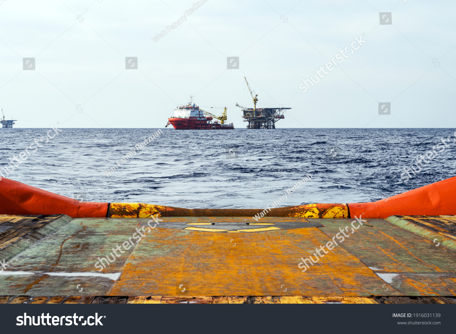 An anchor handling tug boat leaving an offshore oil production platform with a construction vessel moored next to it #1916031139
