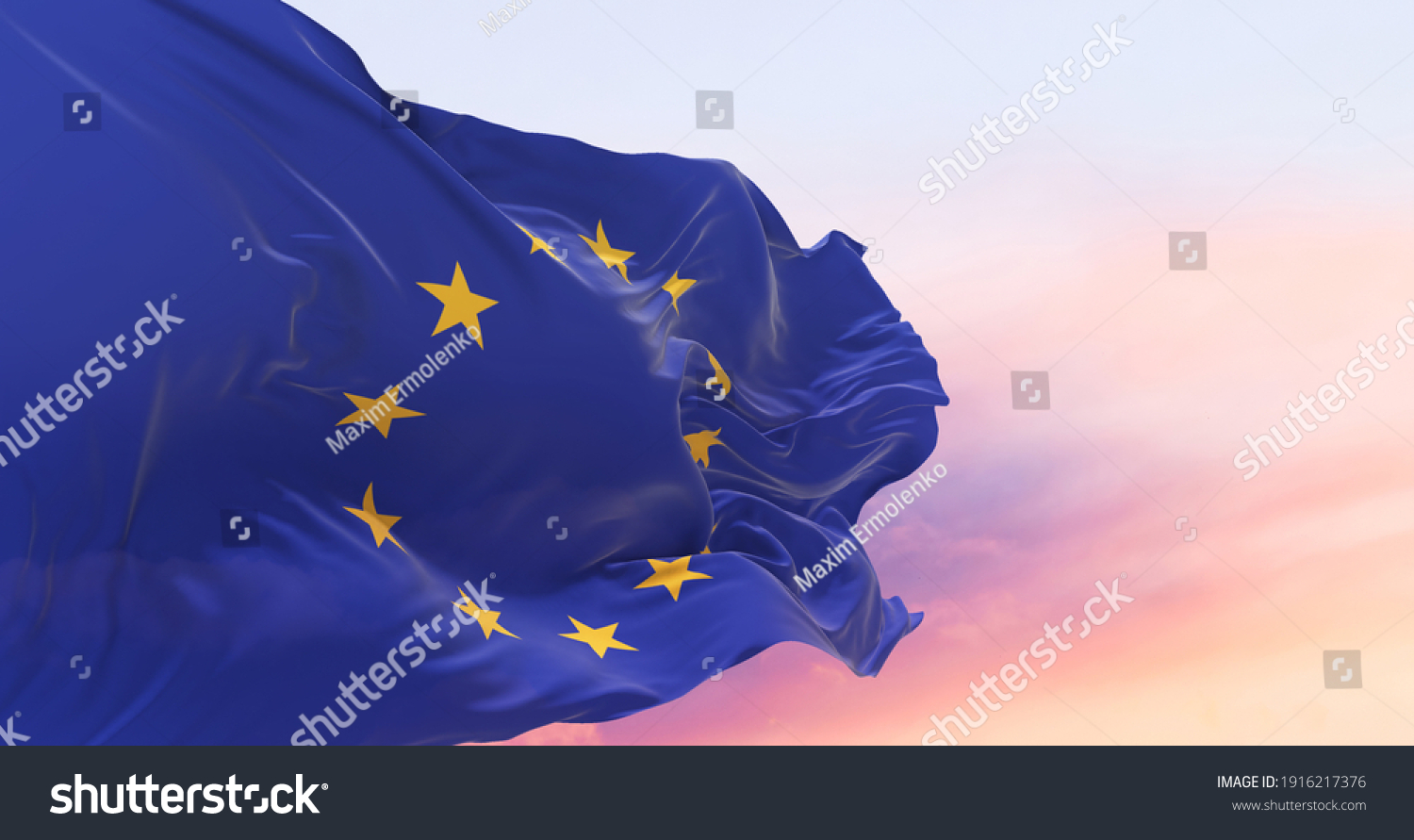 Flag of the European Union waving in the wind on flagpole against the sky with clouds on sunny day #1916217376