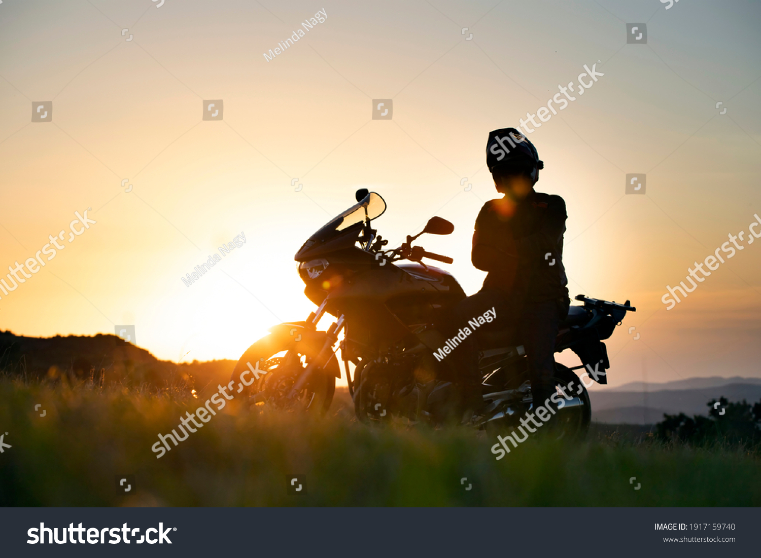 Young motorcycle rider on the road with sunset light background. #1917159740