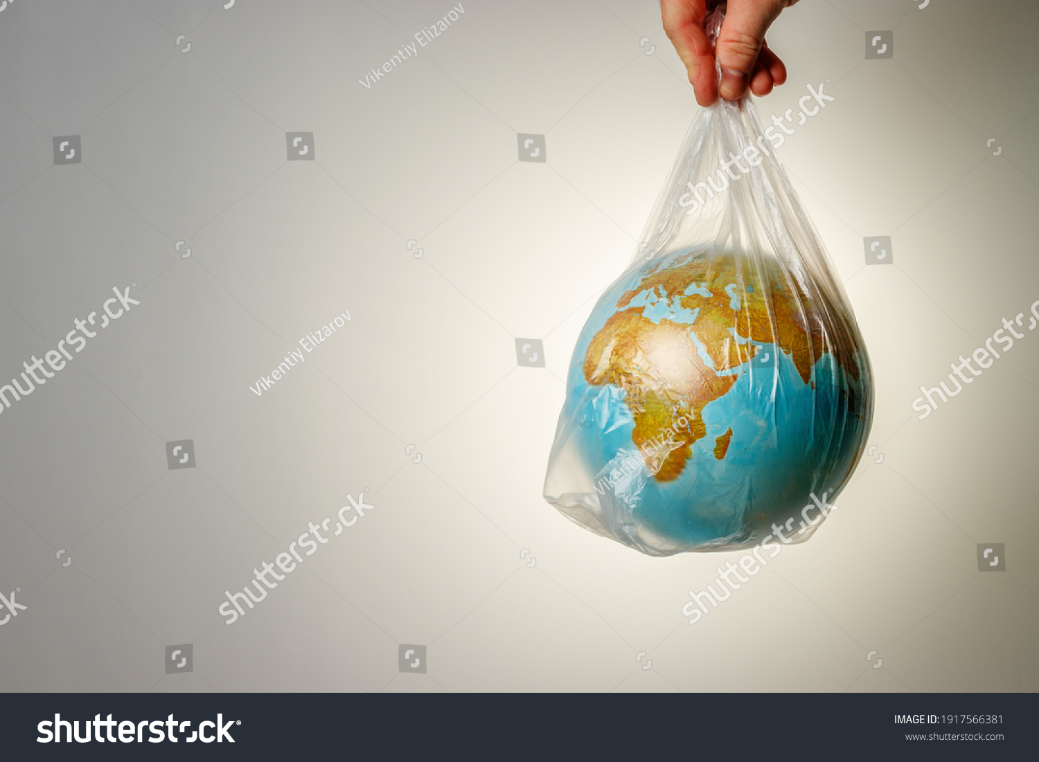 The concept of World Environment Day. The man's hand holds the earth in a plastic bag. In the blank for social advertising there is a place for the inscription. #1917566381