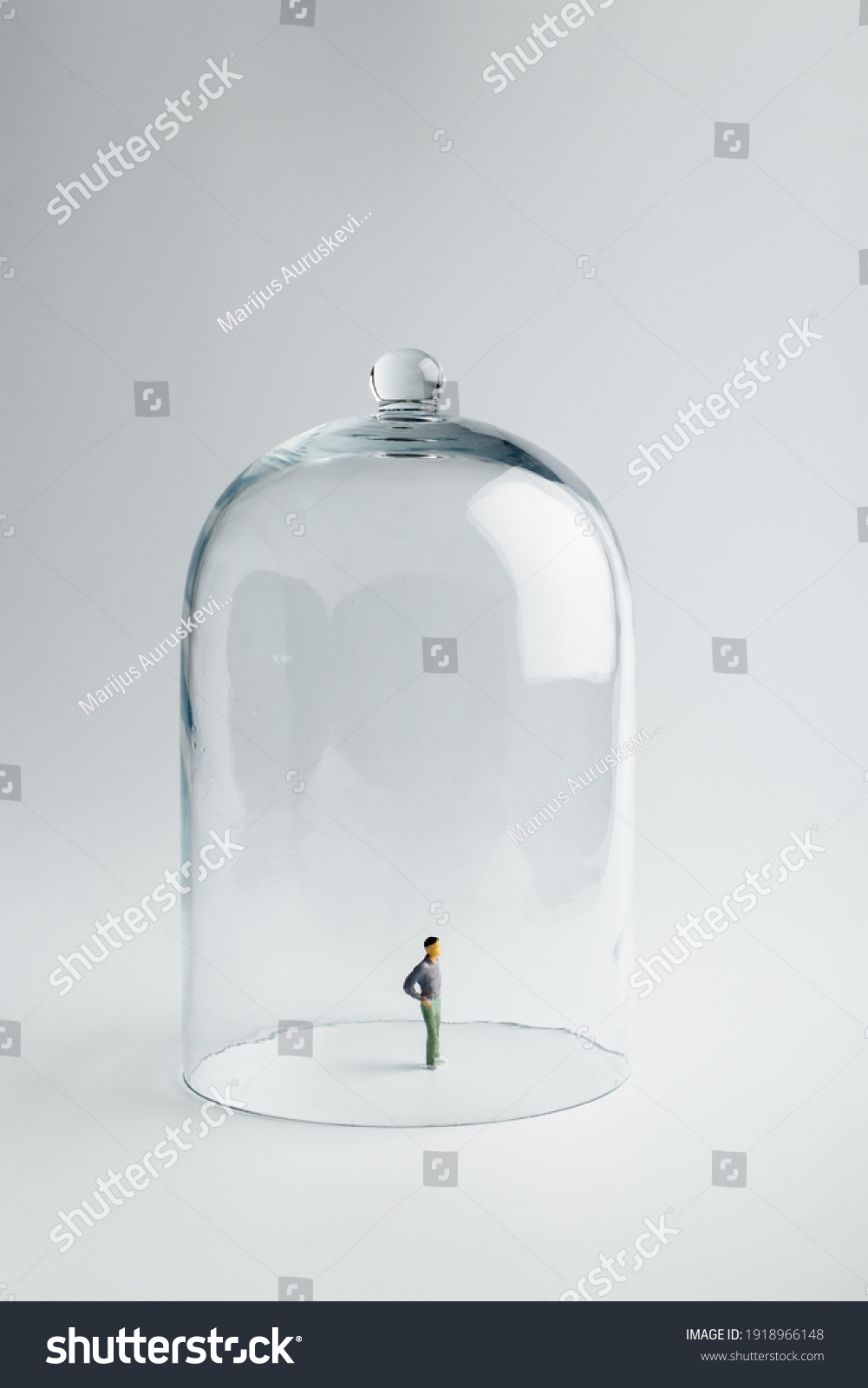 Small figurine in quarantine under a glass dome on a bright background with copy space. Coronavirus prevention, social distancing and Quarantine concept. Self-isolation. #1918966148