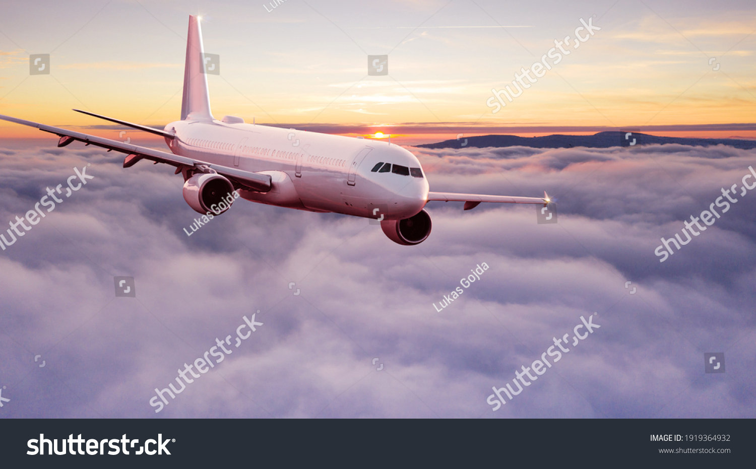 Commercial airplane jetliner flying above dramatic clouds in beautiful light. Travel concept. #1919364932