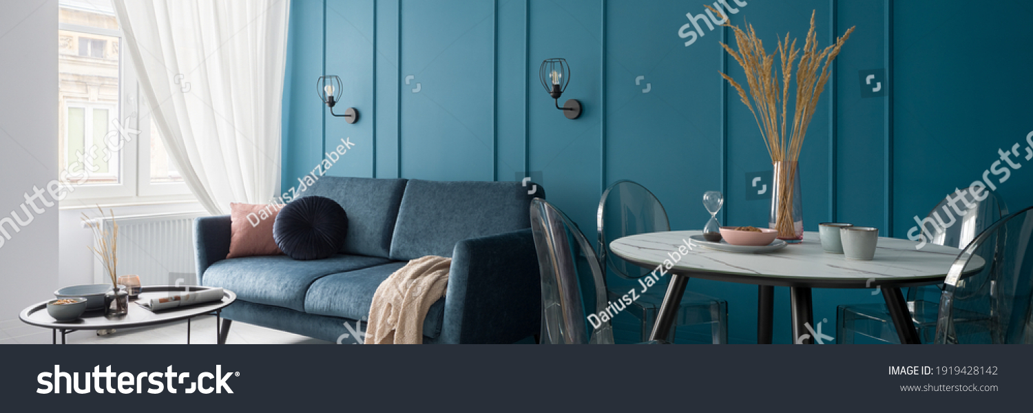 Panorama of small and nice designed living room with modern dining table and stylish blue wall with molding #1919428142