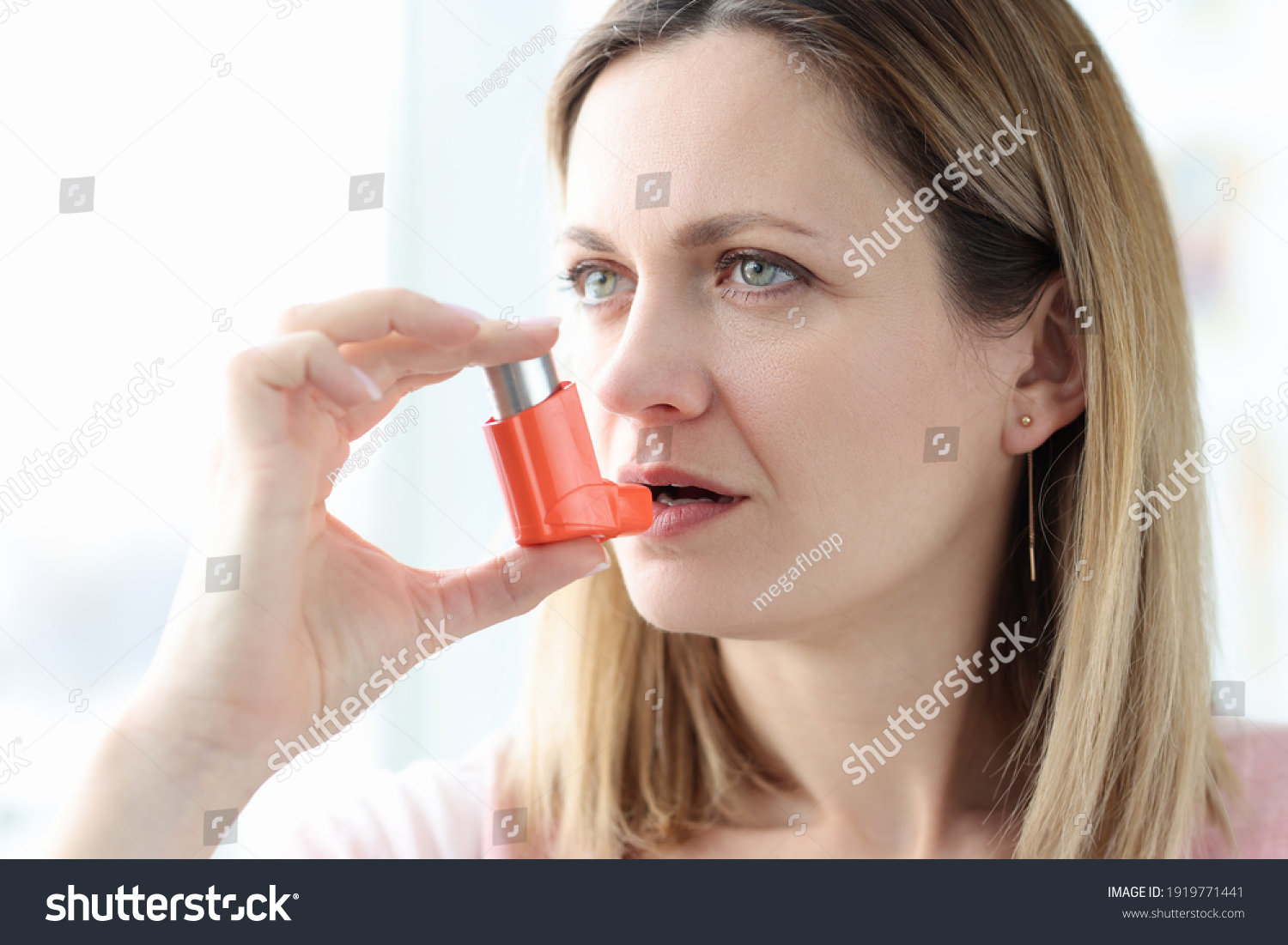 Sick woman holding hormone inhaler near mouth. Treatment of bronchial asthma concept #1919771441