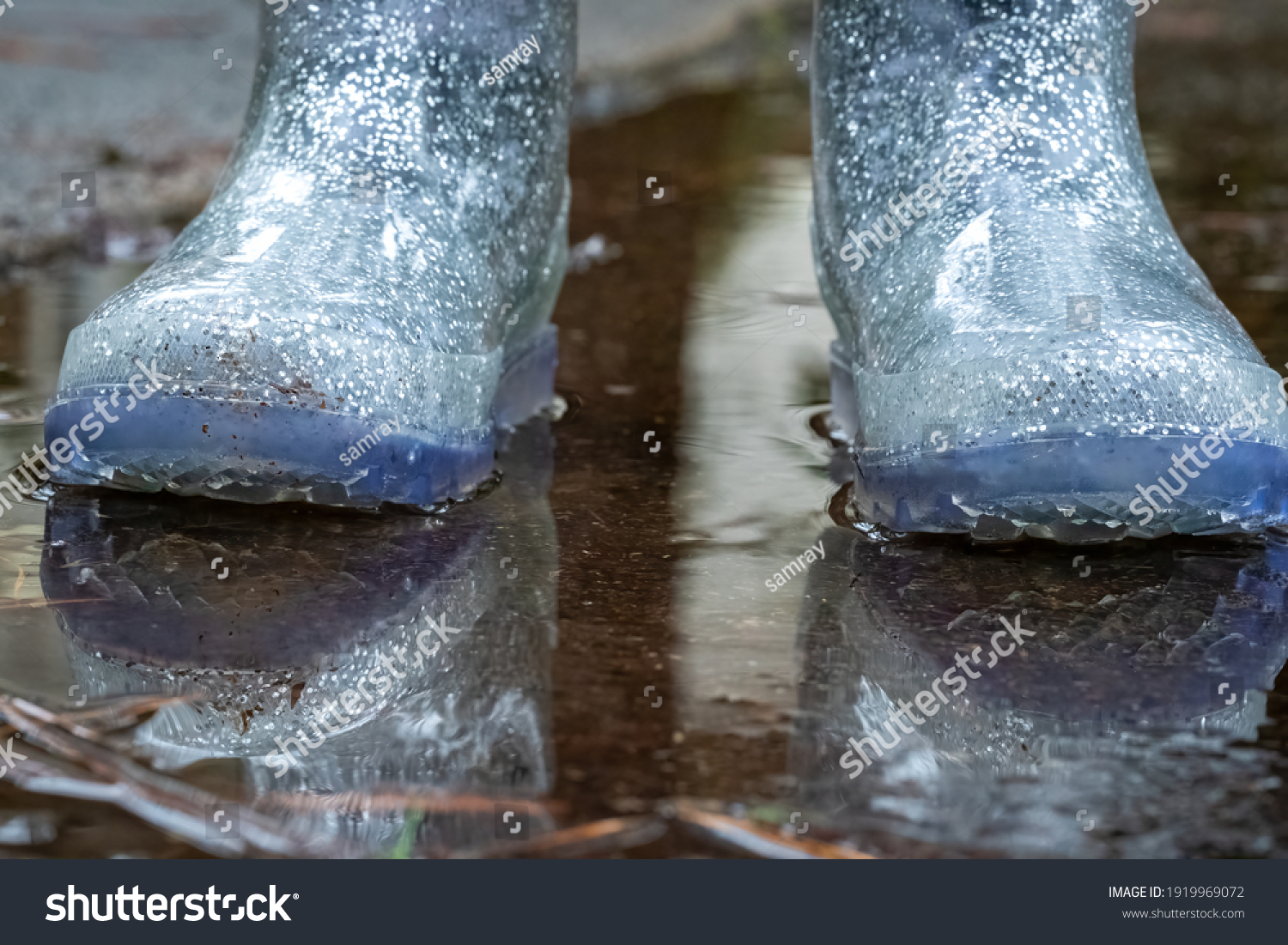 The sparkly blue rainboots of a lttle girl standing in a puddle after a rain shower. #1919969072