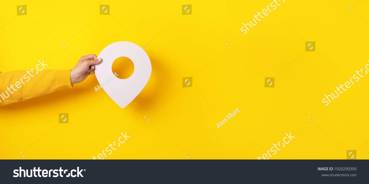 3D location symbol in hand over yellow background, panoramic image #1920290390