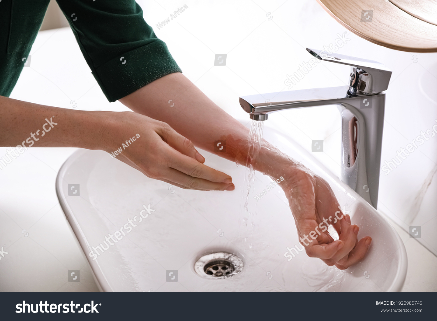 Woman putting burned hand under running cold water indoors, closeup #1920985745