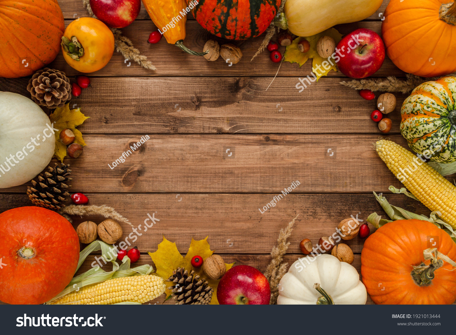 Variety of gourds, squash types and pumpkins. Flat lay composition frame with walnuts, hazelnuts, apples, cones, rosehips, kaki and corn on the cob. Copyspace on wooden background. #1921013444