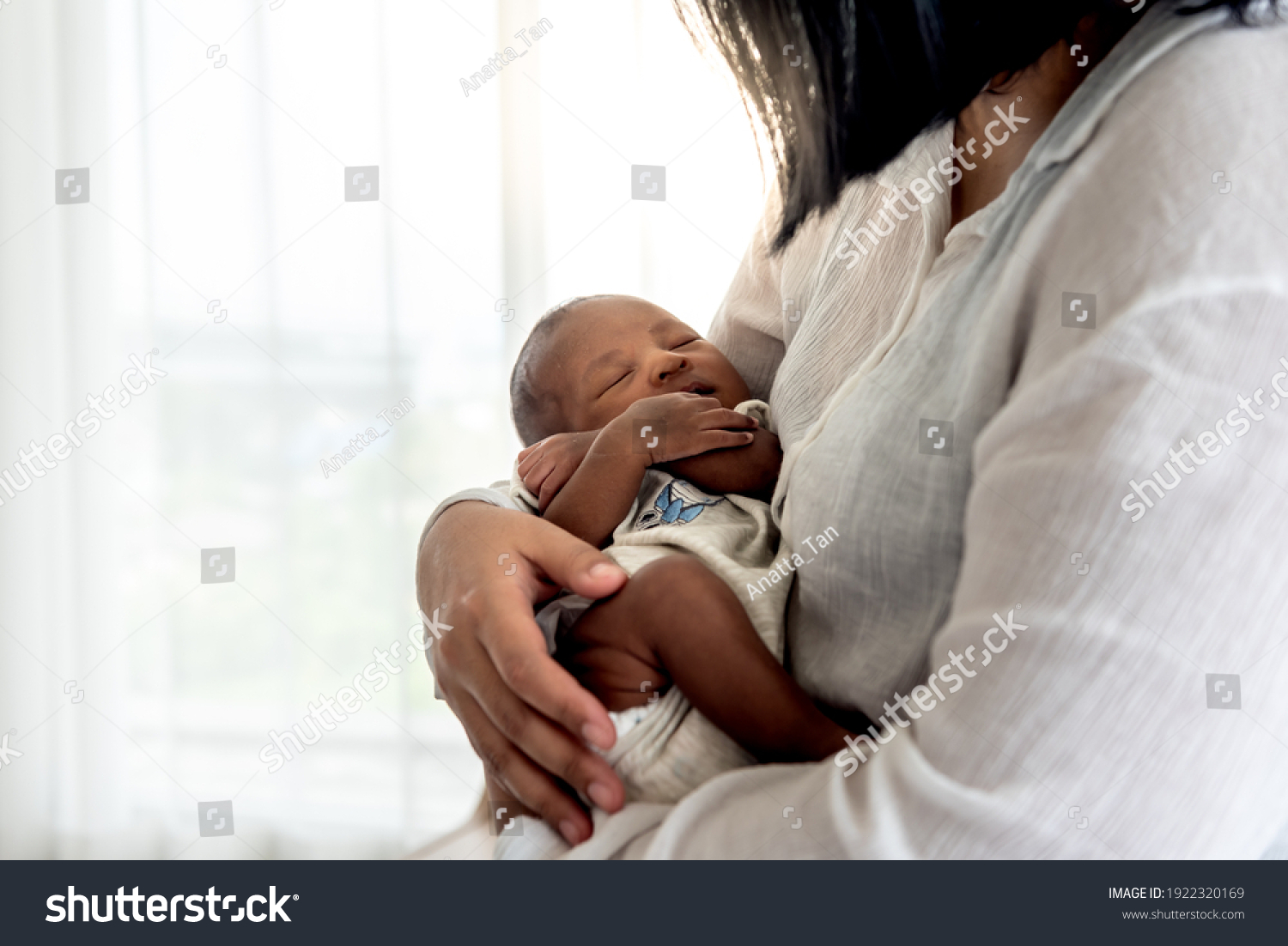 Portrait images of half African half Thai, 12-day-old baby newborn son, sleeping with his mother being held, to family and infant newborn concept. #1922320169