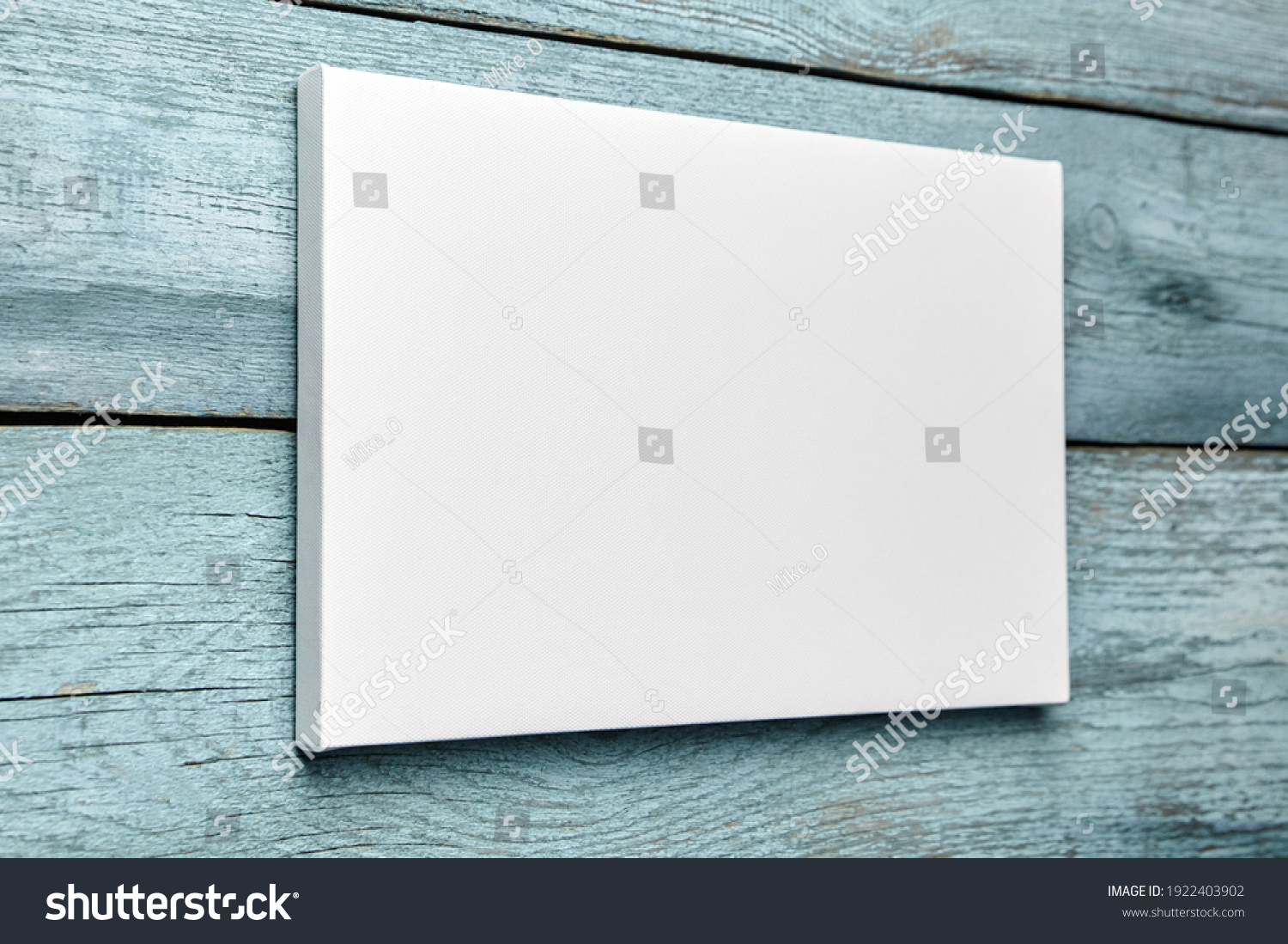 White canvas hanging on light blue wooden wall. Mockup, wall decor, blank canvas stretched on stretcher bar, side view #1922403902