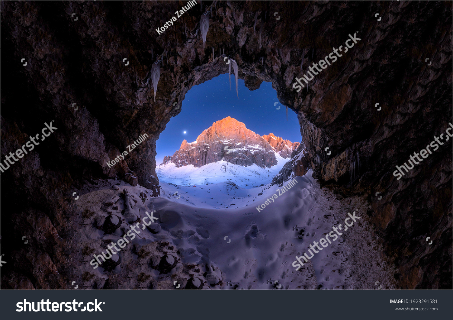 Cave entrance in winter snow mountains. Winter mountain snow cave. Cave hole in winter snow mountains. Cave in winter mountain snow #1923291581