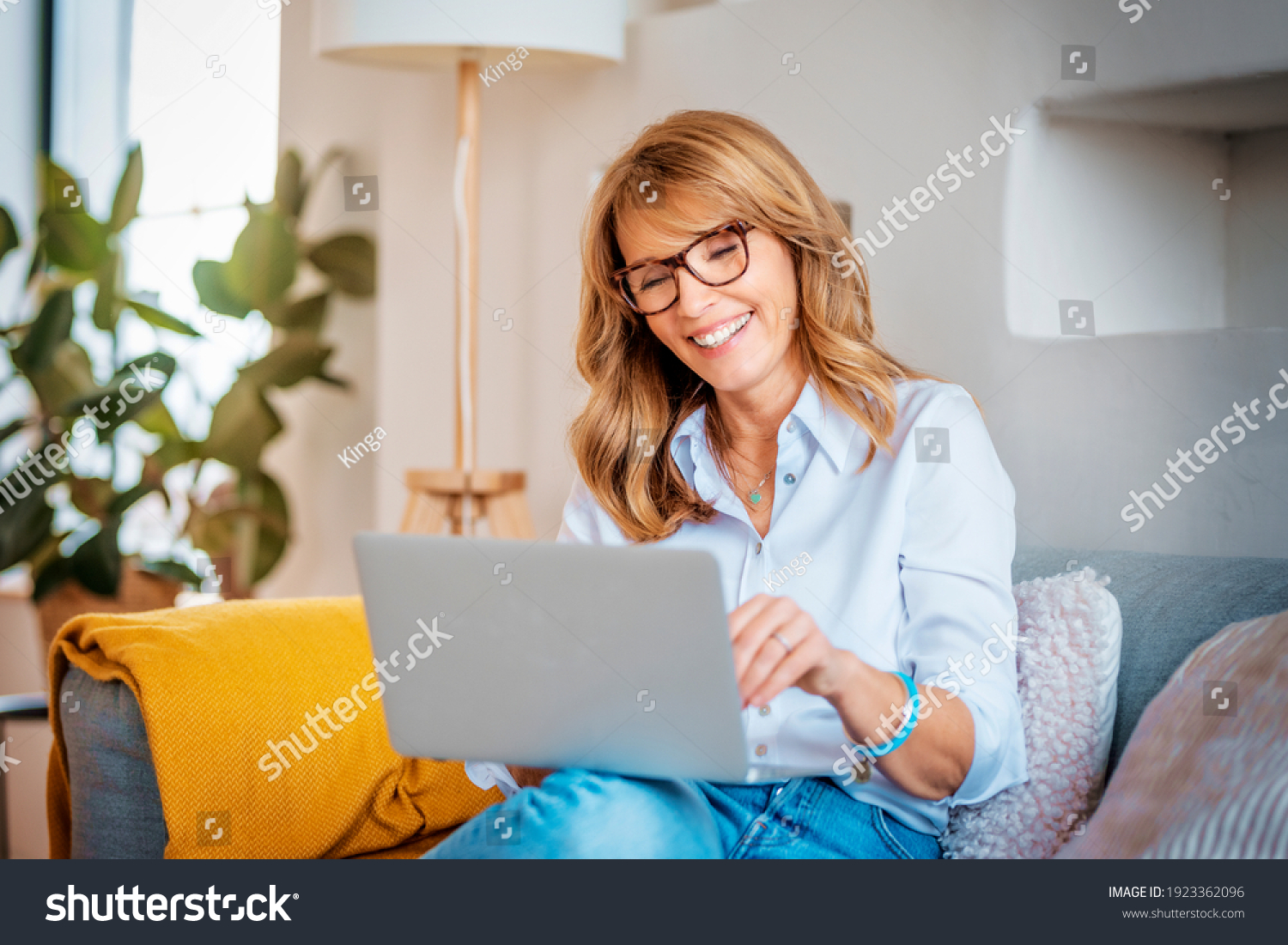 Shot of a happy middle aged woman using her laptop on the sofa at home.  #1923362096