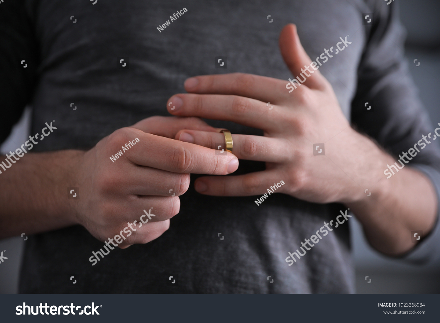 Man taking off wedding ring on blurred background, closeup. Divorce concept #1923368984