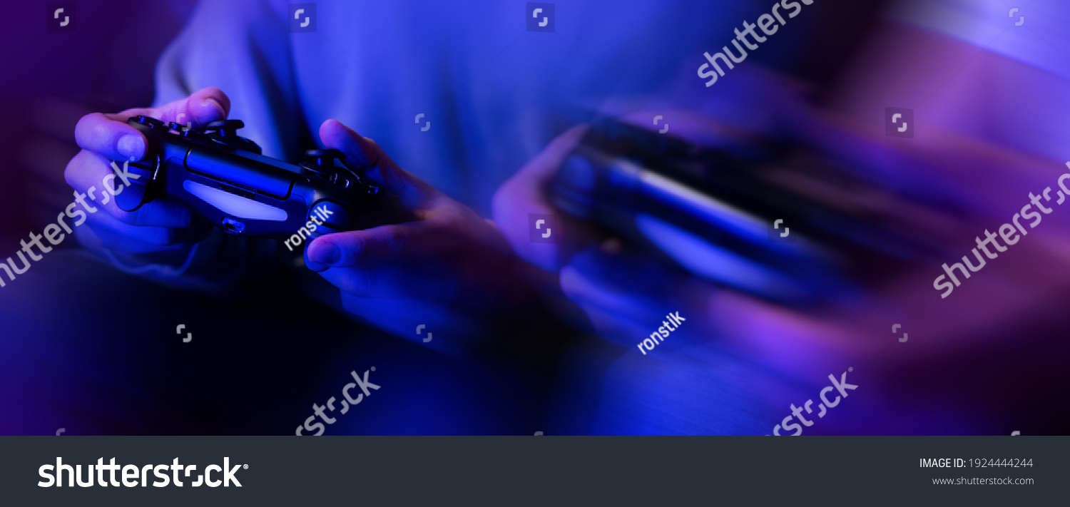 gamers playing console video games. controller in hands closeup. neon lights banner #1924444244