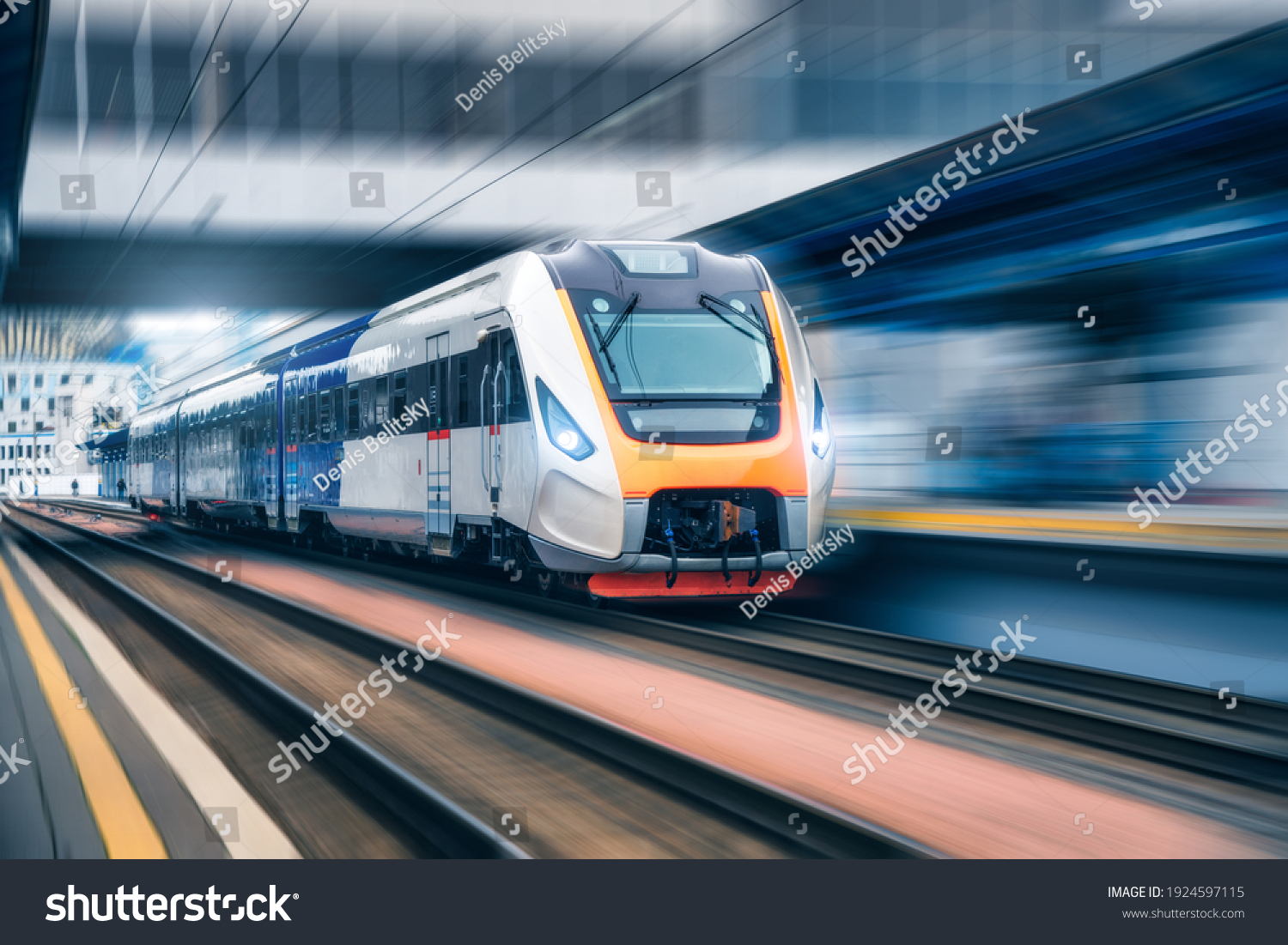 High speed train in motion on the railway station at sunset. Modern intercity passenger train with motion blur effect on the railway platform. Industrial. Railroad in Europe. Transportation. Industry #1924597115