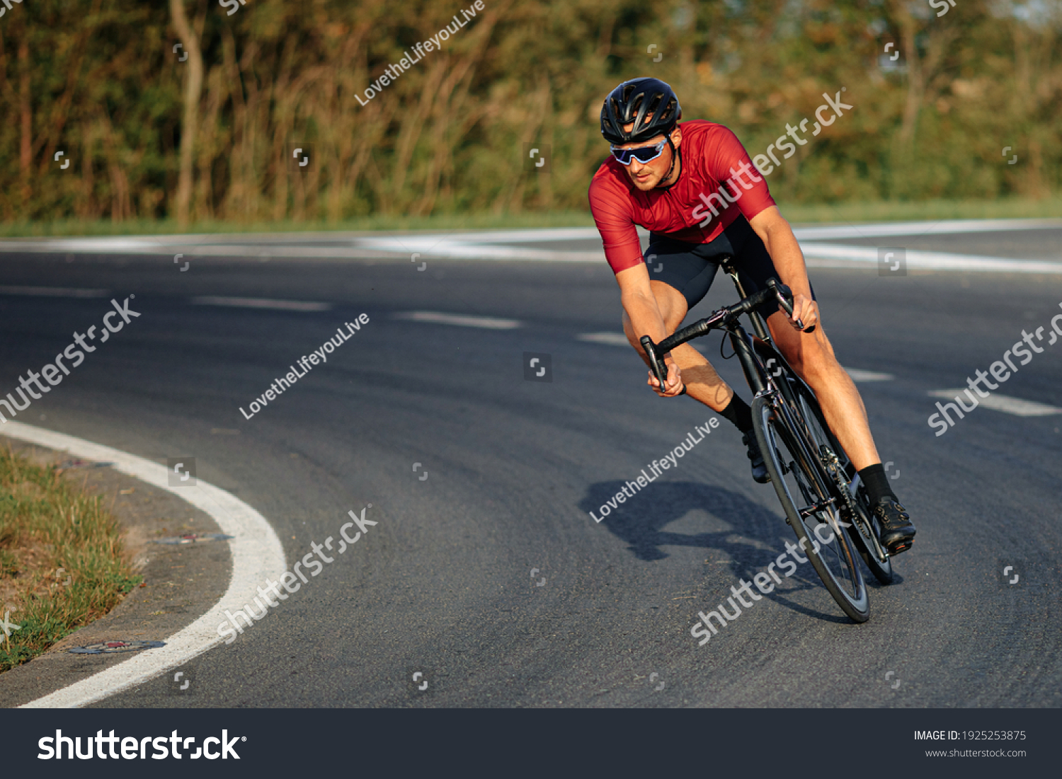 Muscular young guy wearing sport clothing, protective helmet and mirrored glasses enjoying sport activity on black bike. High speed and racing. #1925253875