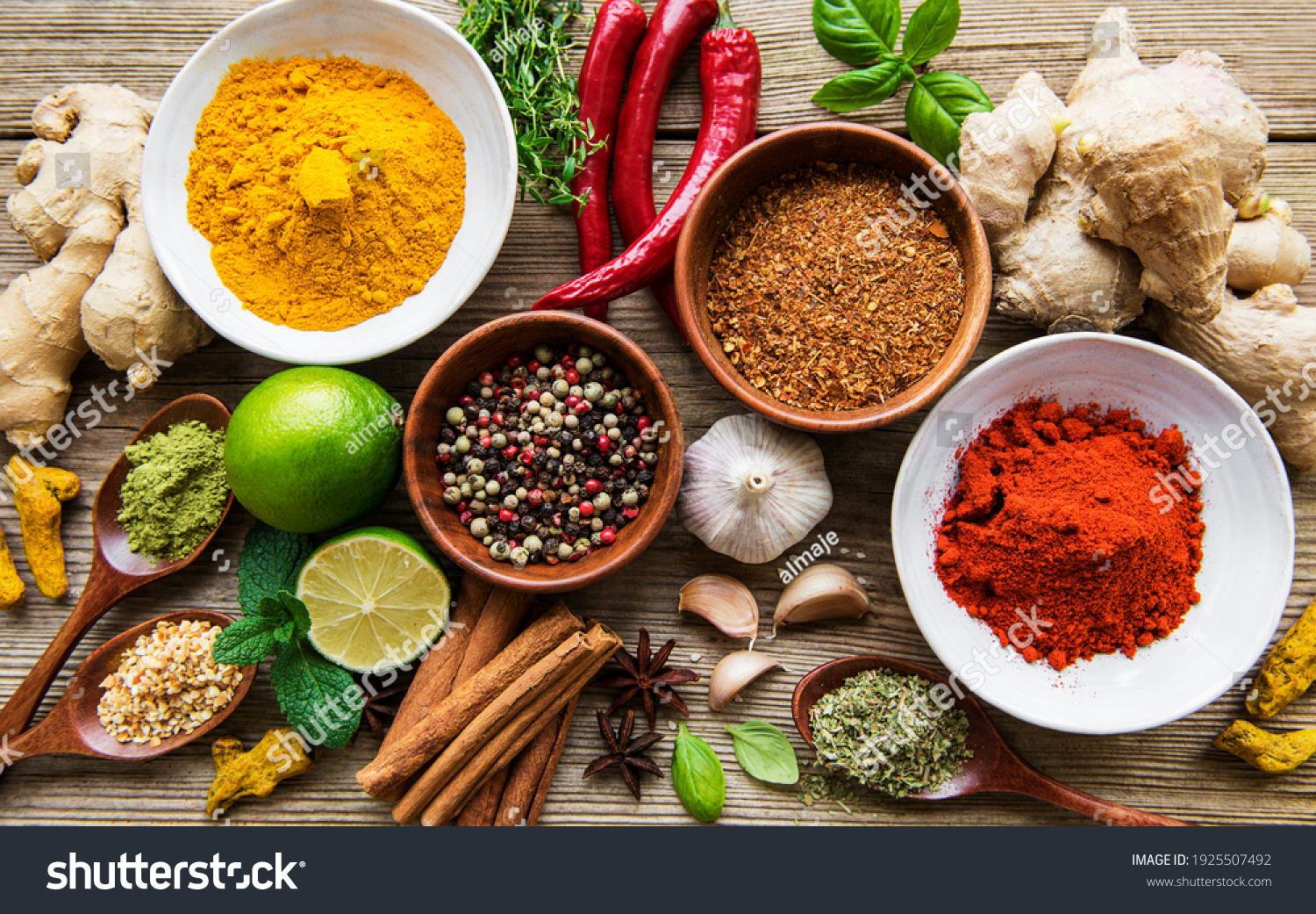 A selection of various colorful spices on a wooden table in bowls and spoons #1925507492