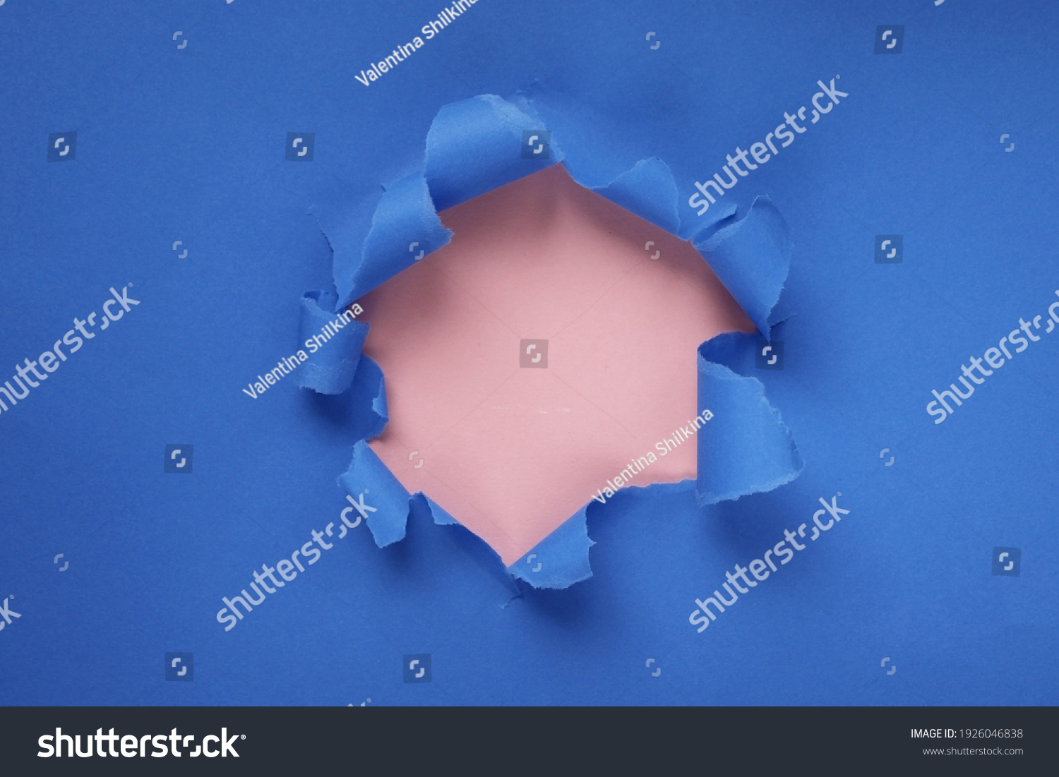 Paper hole with torn sides on a blue-pink background. Through the paper. A ragged hole.An accurate shot. The concept of advertising and breakthrough. Design for text, print, or advertising content. #1926046838