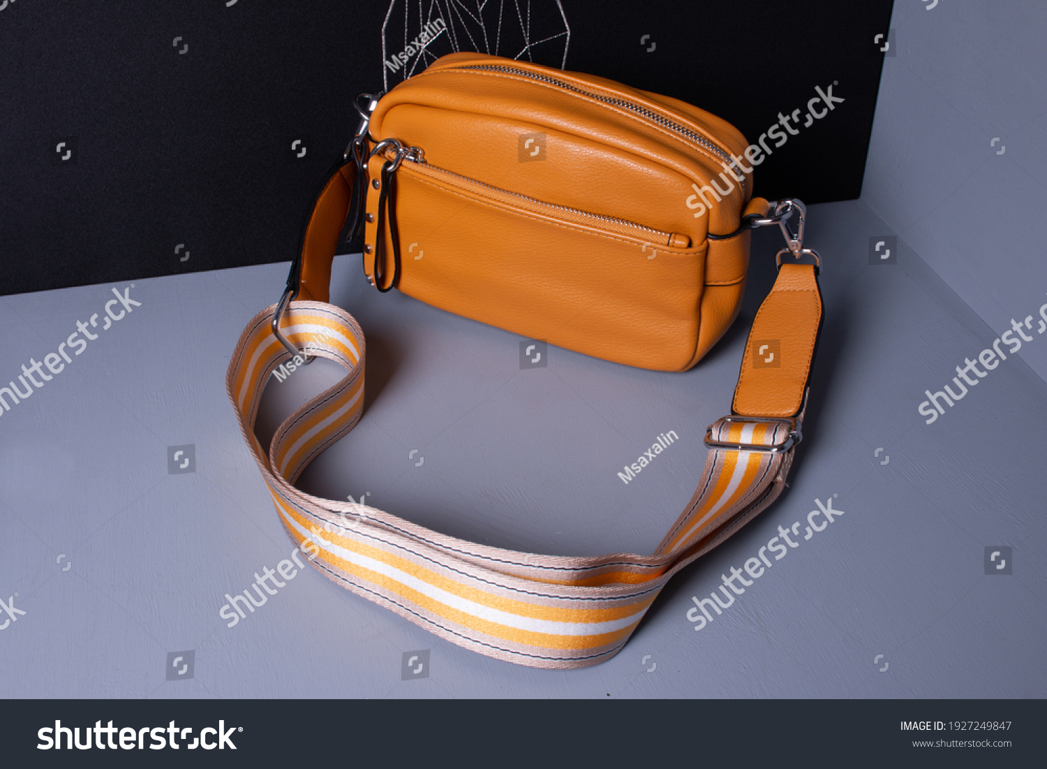 Women's yellow bag with a wide textile belt. Cross body made of artificial leather. Gray and black background. #1927249847