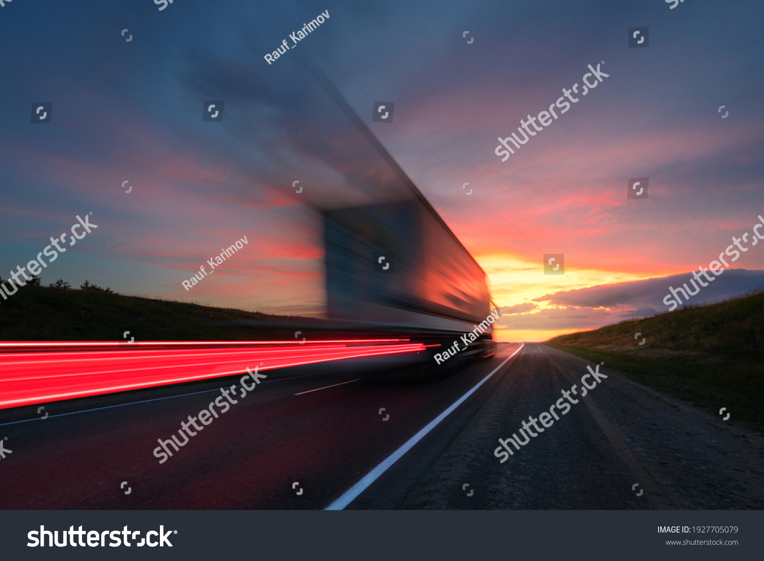 Blurring. A large truck is driving along the highway at high speed. Sky with bright red clouds. Delivery of cargo. #1927705079