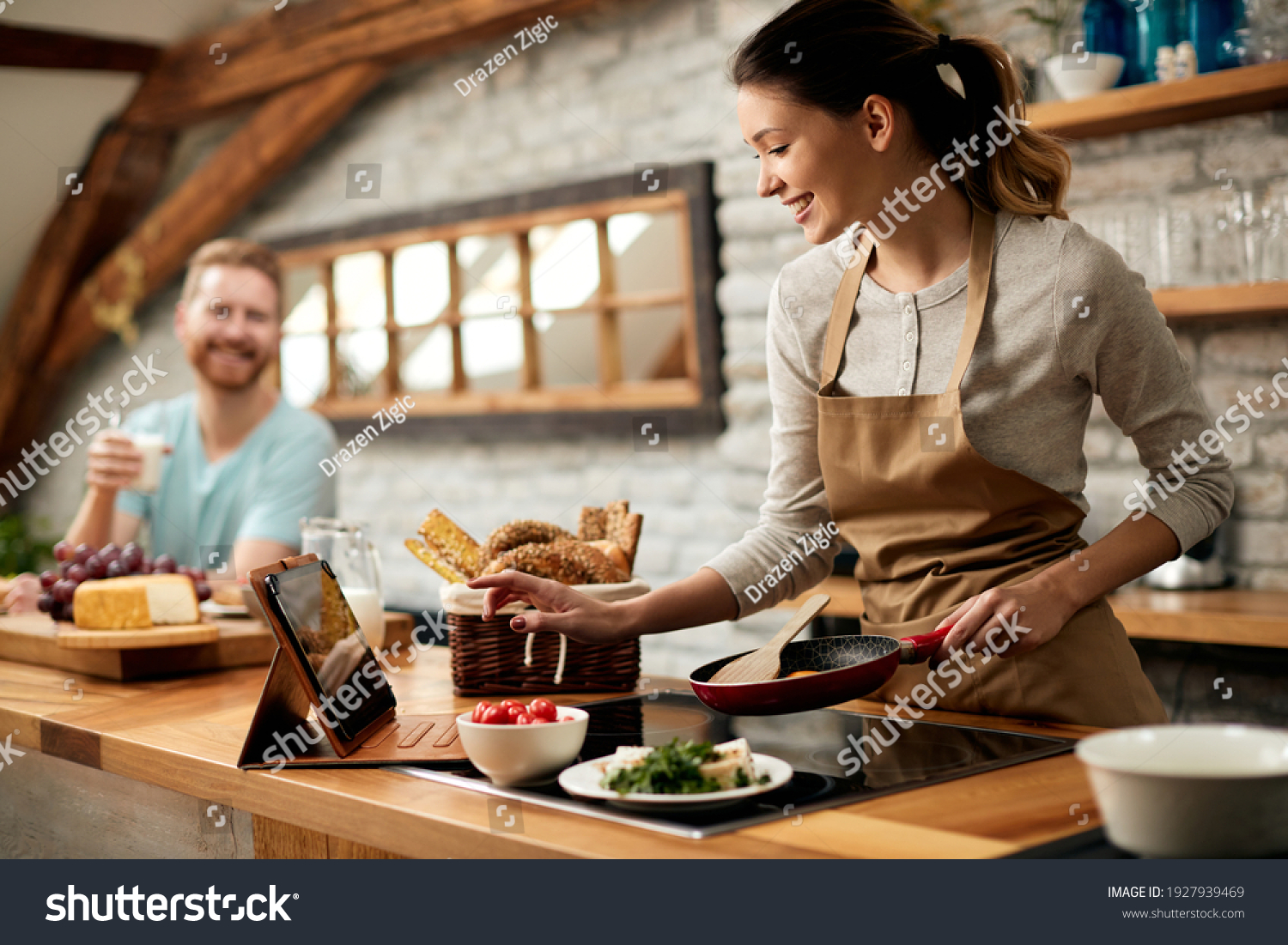 Happy woman preparing food while following recipe on digital tablet in the kitchen.  #1927939469