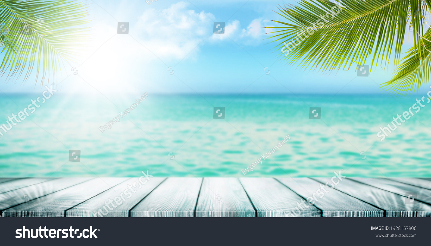 Summer tropical sea with waves, palm leaves and blue sky with clouds. Perfect vacation landscape with empty wooden table #1928157806