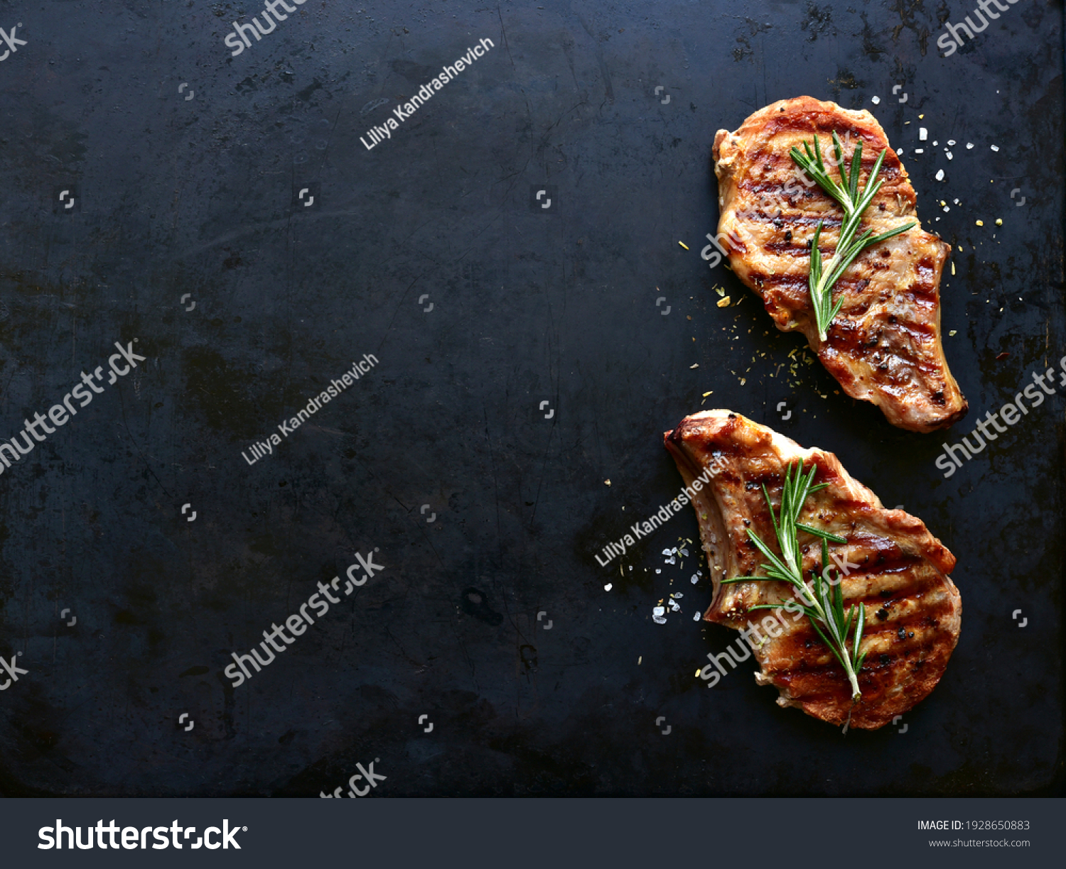 Grilled pork loin on a bone on a black metal background. Top view with copy space. #1928650883