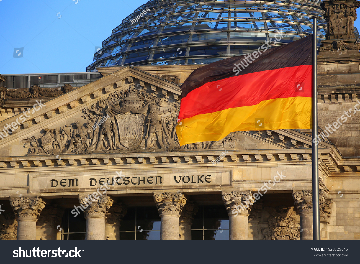 The German flag in front of the Reichstag building in Berlin. The inscription says: Dem Deutschen Volke - To the German people. #1928729045
