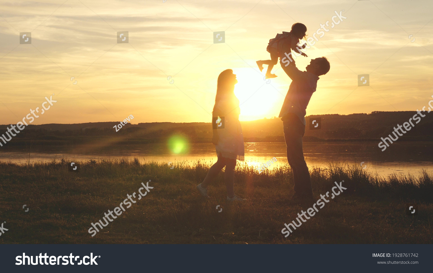 Child in the hands of parents jumps from dad to mom and laughs. Happy family walk on the beach at sunset. Child, daughter, mom, dad play fun in park in park in sun. Family fantasies, childhood dreams. #1928761742