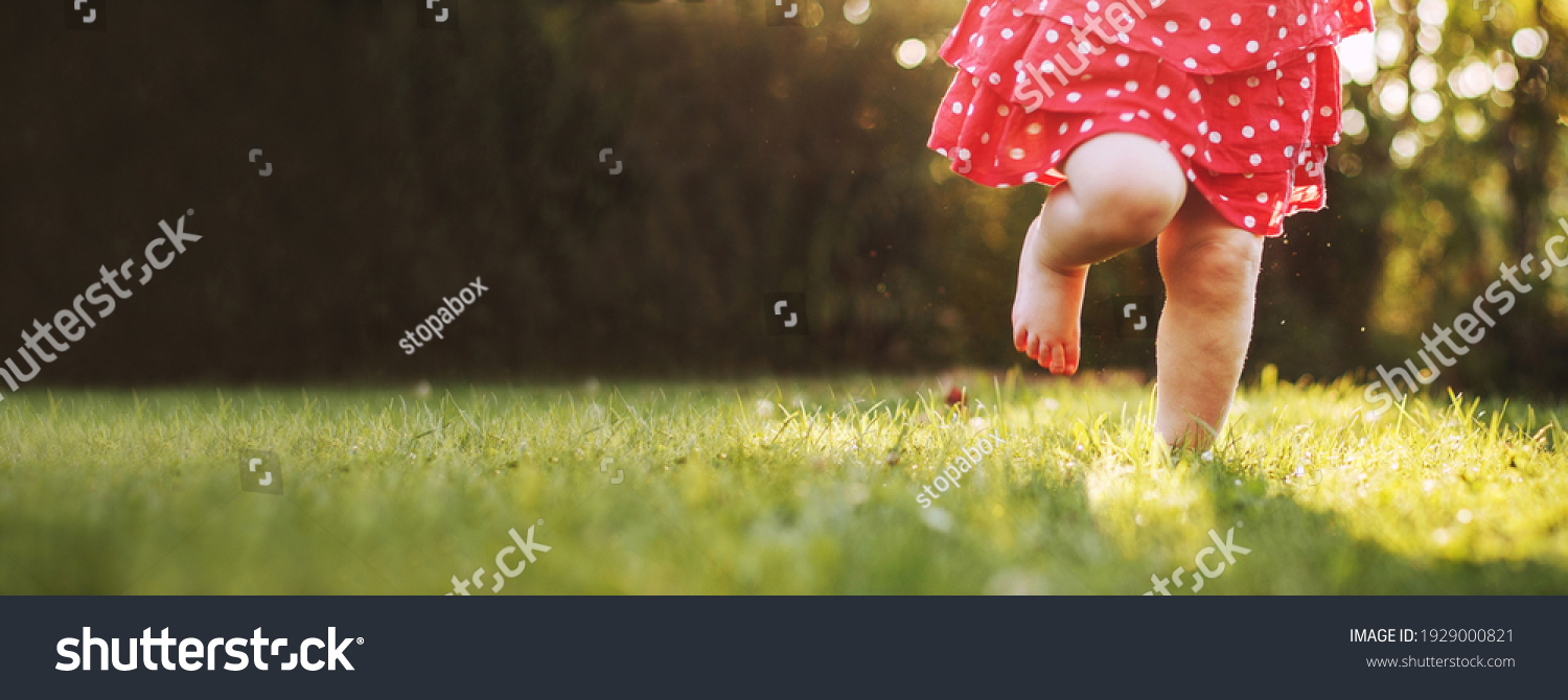 girl's bare feet in the green grass. little Happy child running at sunset barefoot outdoor. Concept of happy childhood #1929000821