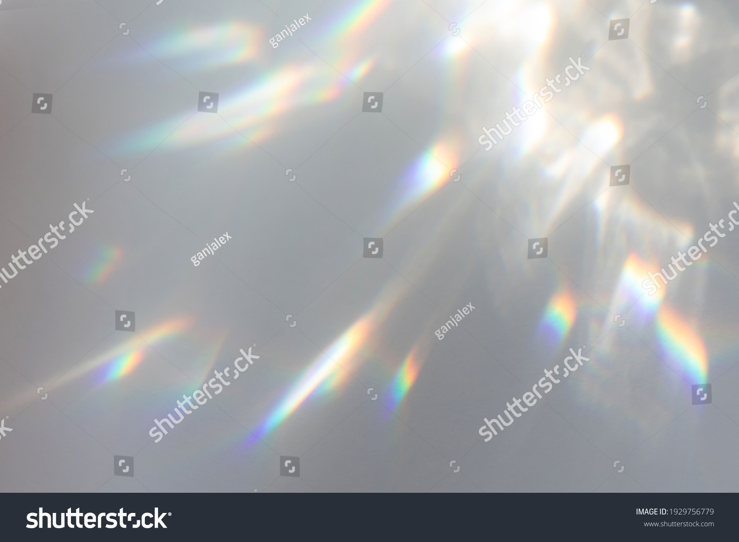 Blurred rainbow light refraction texture overlay effect for photo and mockups. Organic drop diagonal holographic flare on a white wall. Shadows for natural light effects #1929756779