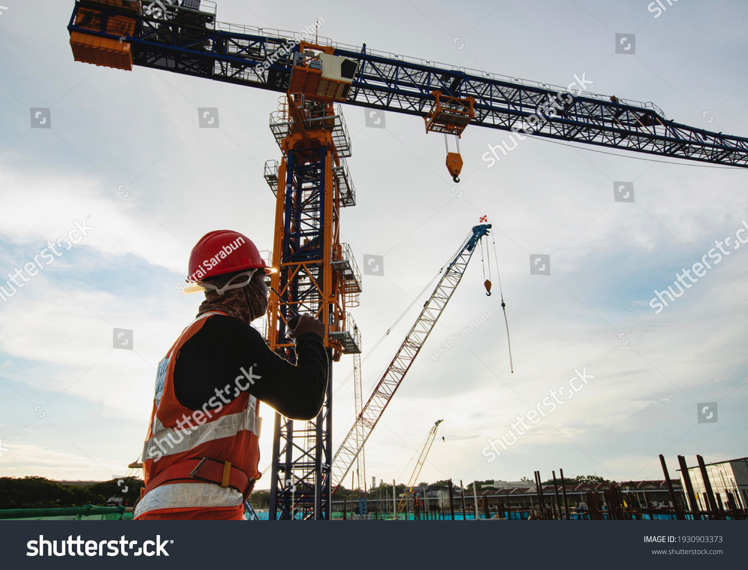  Rigger signal crane at construction site with walkie;talkie  #1930903373
